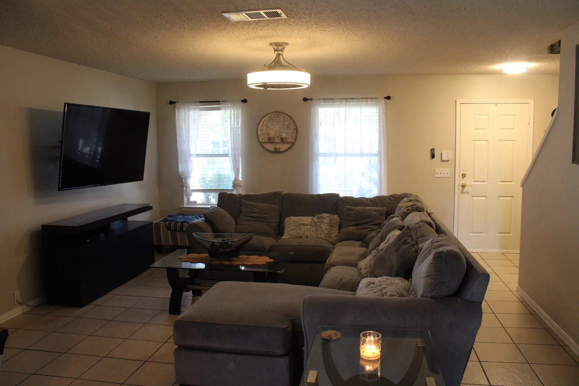Recessed ceiling light, two windows with white window treatments, overhead ceiling fan with integrated lighting, paneled entry door, and tiled flooring