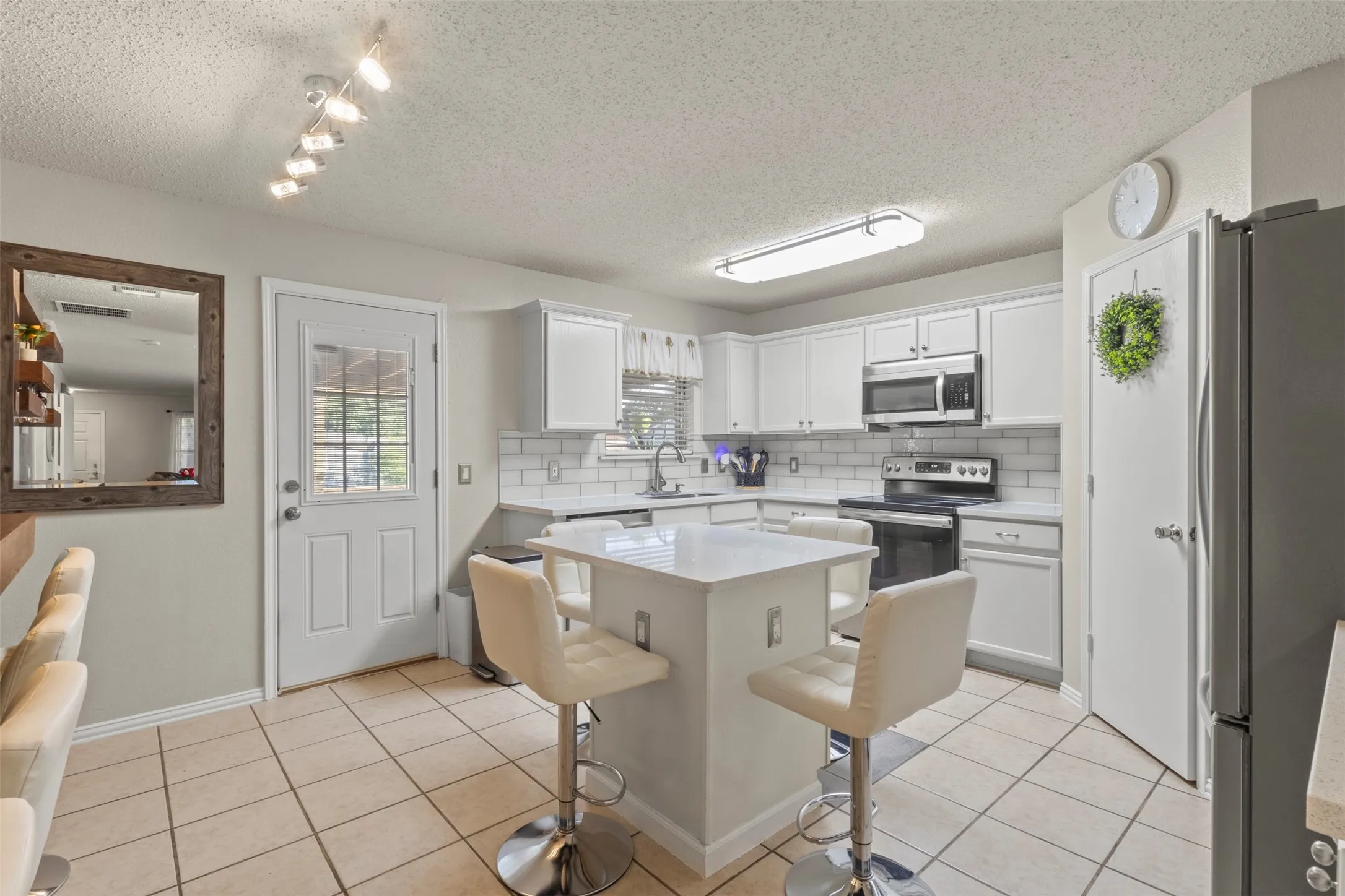 Kitchen featuring a central island, white cabinetry, subway tile backsplash, and tile flooring