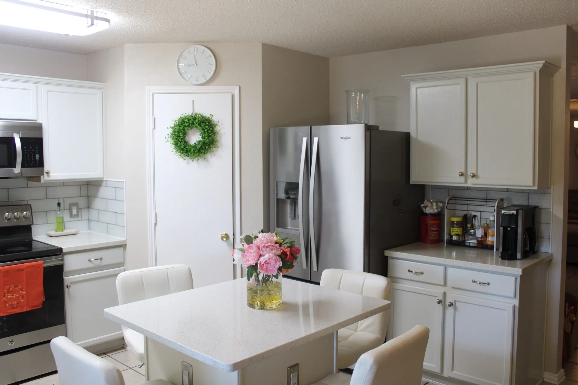White shaker-style cabinetry with crown molding, stainless steel appliances, subway tile backsplash, and light-toned countertops