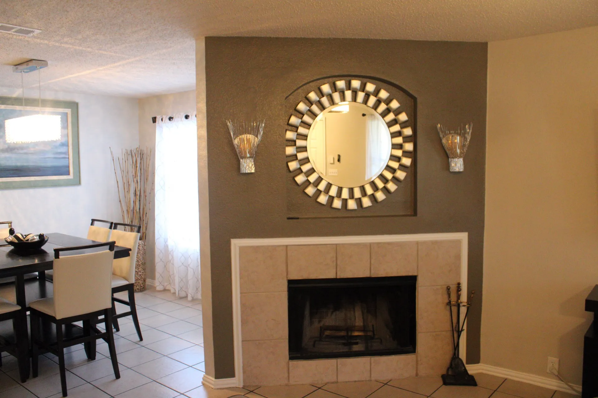 Tile flooring, fireplace with tile surround, built-in wall niche, decorative wall sconces, and a rectangular pendant light fixture