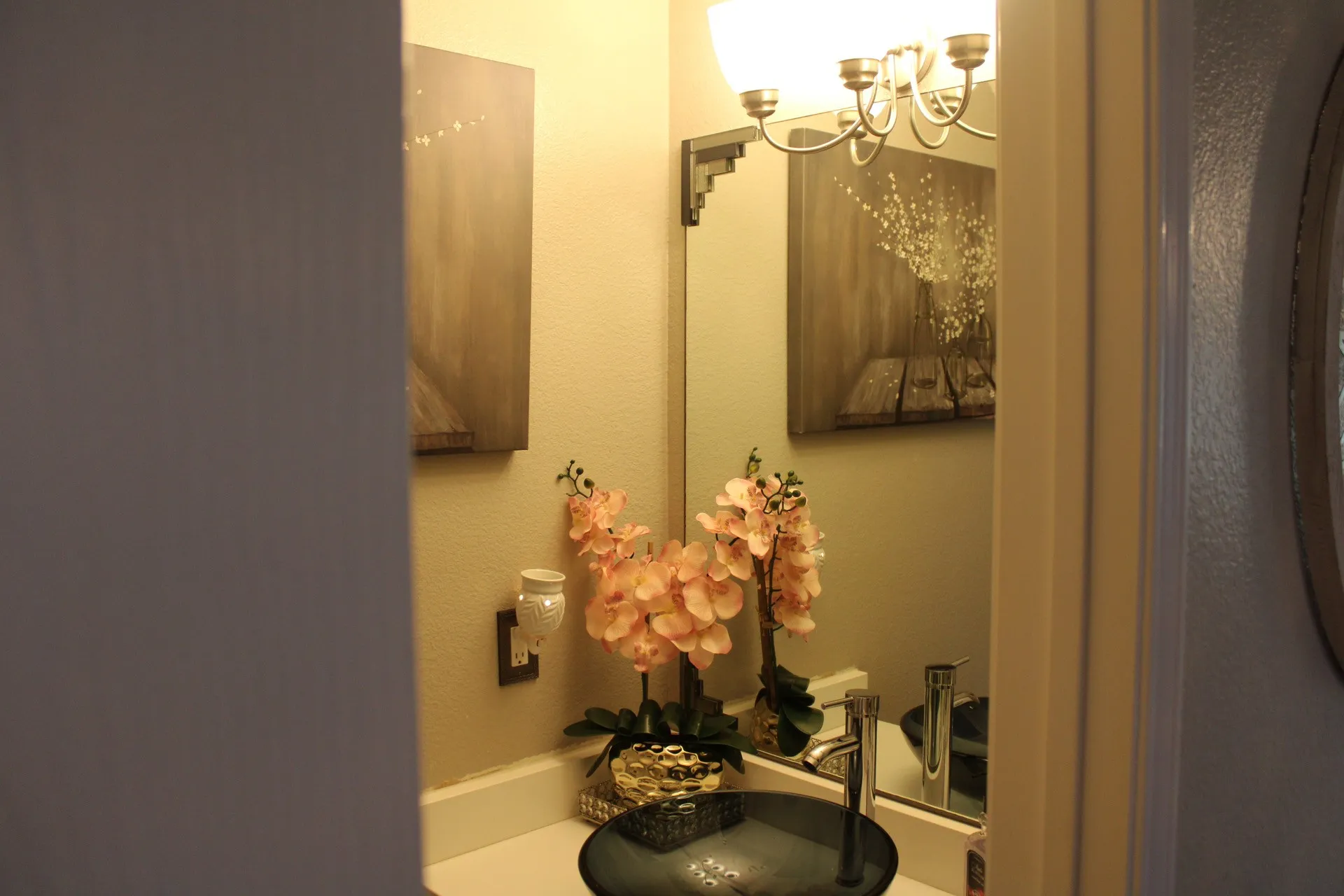 Vessel sink with a chrome faucet, mounted mirror, and a vanity light fixture