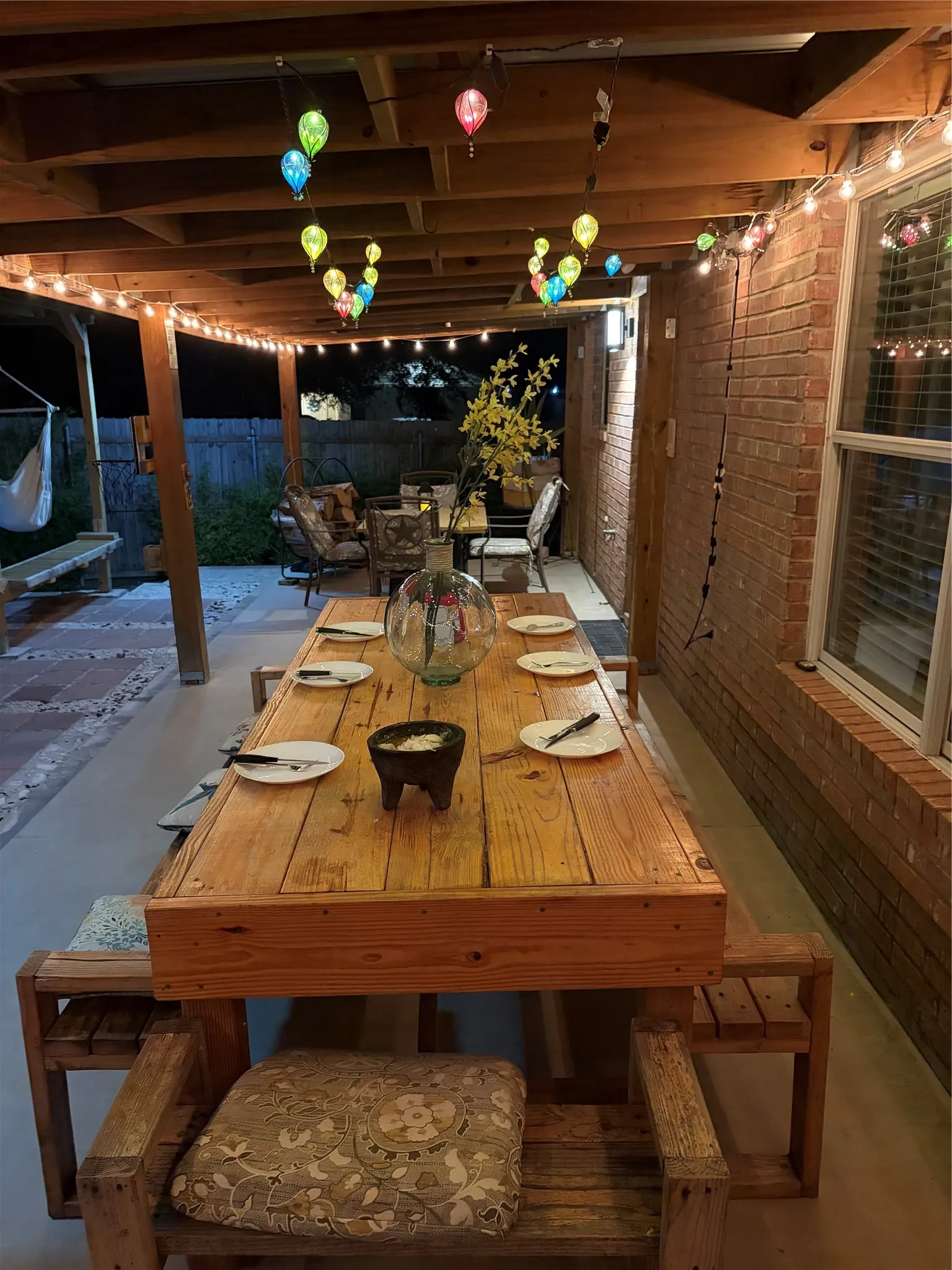 Expansive covered patio featuring a wood-beam ceiling, brick exterior wall, and concrete flooring