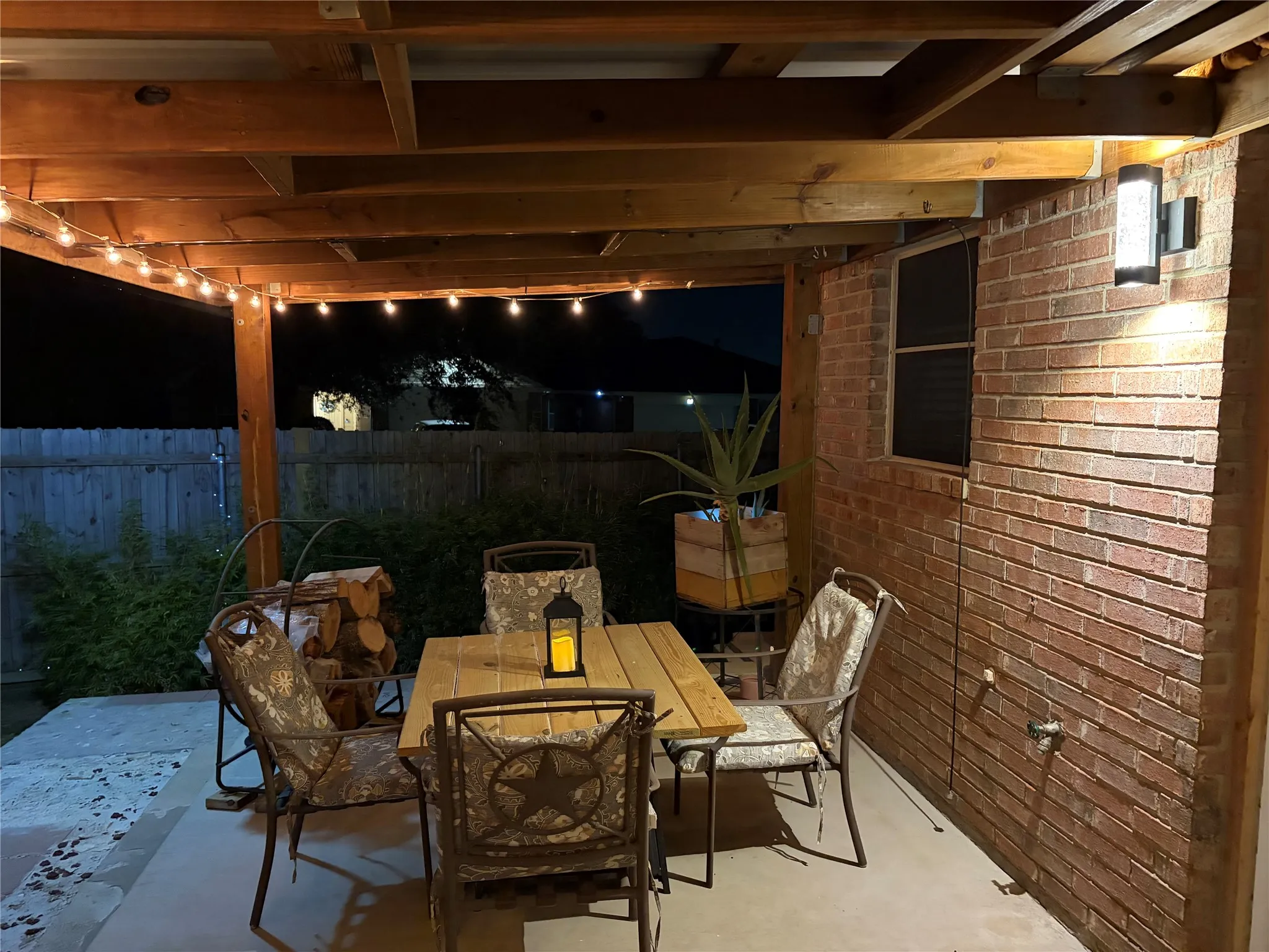 Covered patio with exposed wood beam ceiling, concrete flooring, and red brick exterior wall