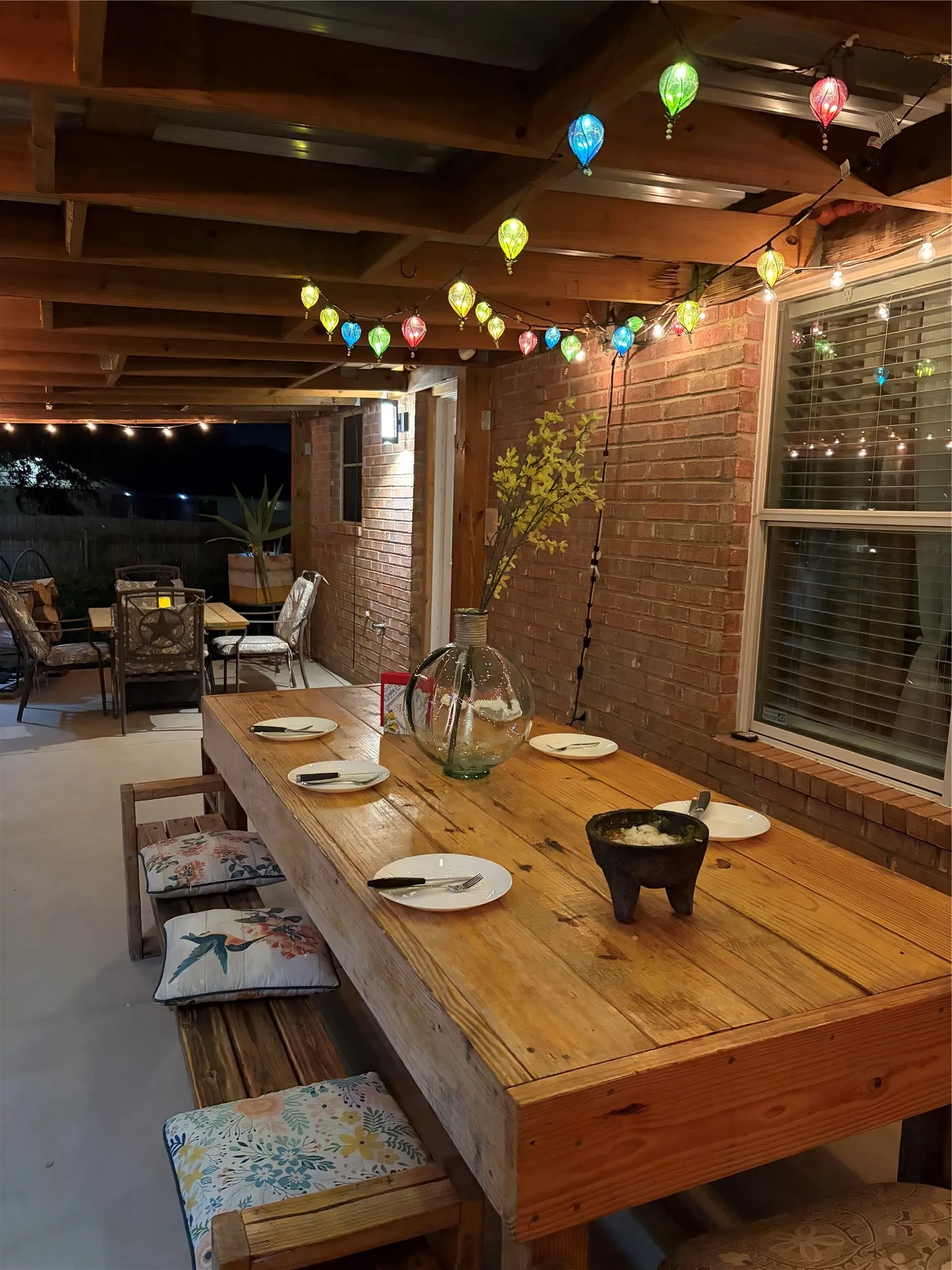 Covered patio featuring a wood beam ceiling, brick exterior wall, and a large wood table