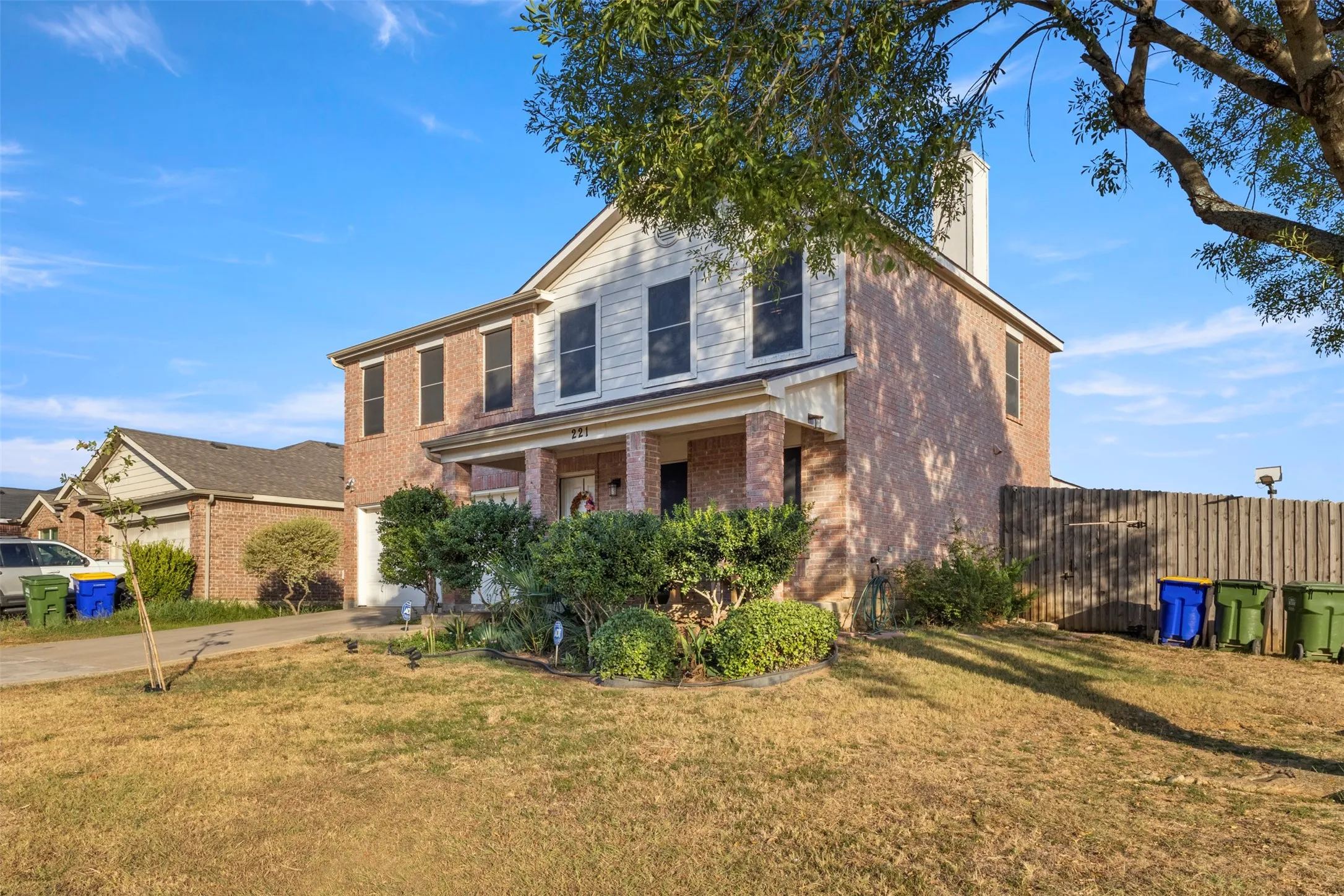Two-story residence featuring a brick facade, covered front porch, and a white chimney