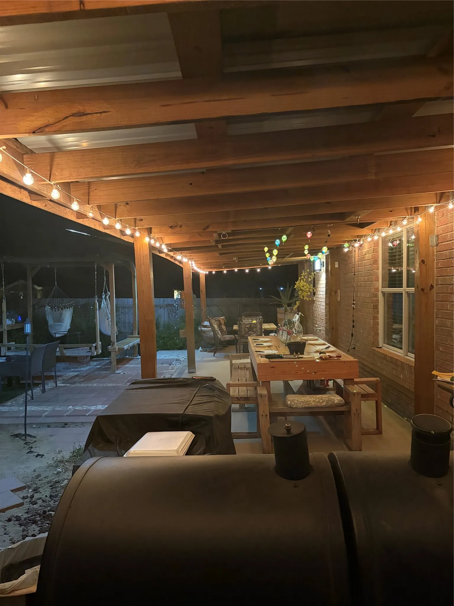 Covered patio featuring exposed wood beams and string lighting