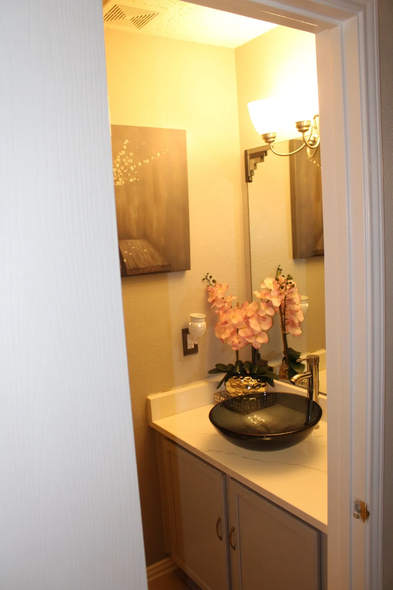 Vanity with a vessel sink and single-handle faucet, integrated mirror, and wall-mounted light fixture