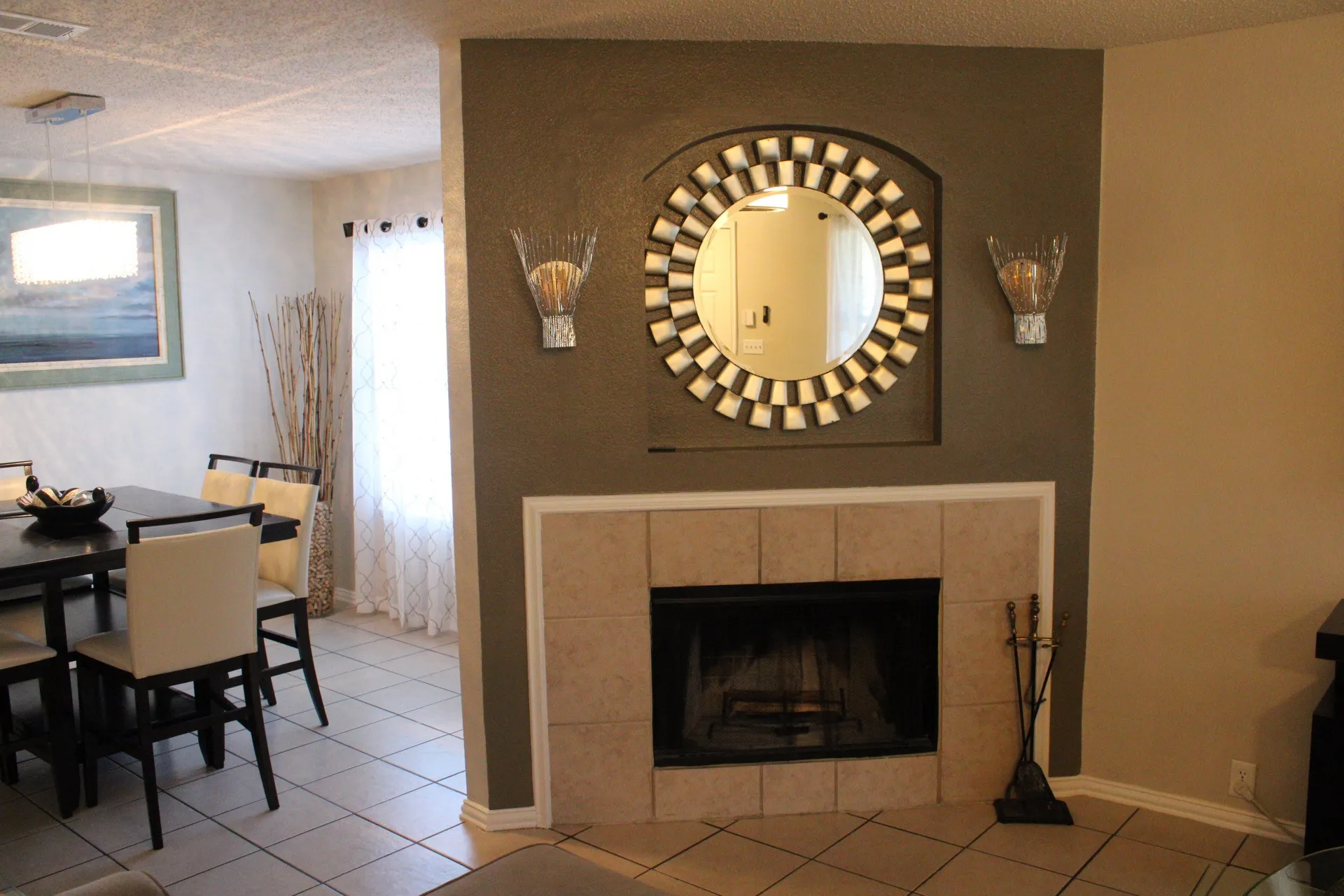 Tile flooring throughout, a built-in fireplace with a tile surround, and a rectangular window with sheer curtains