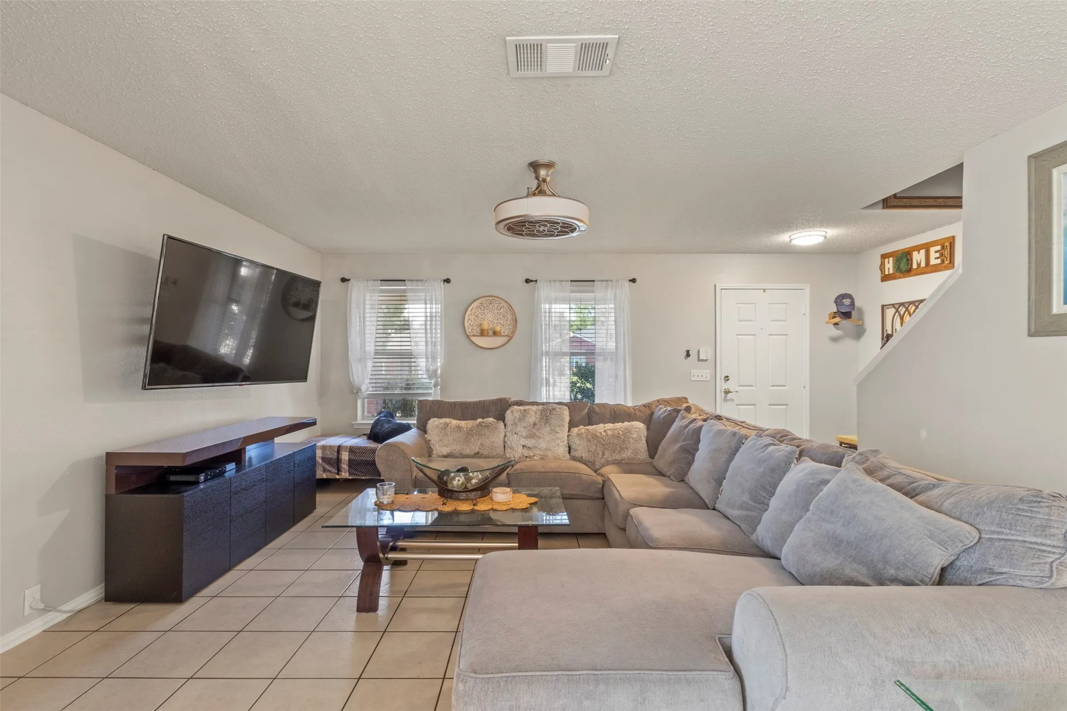 Tile flooring, white wall paint, flush-mount ceiling light, white paneled door, and a built-in media console