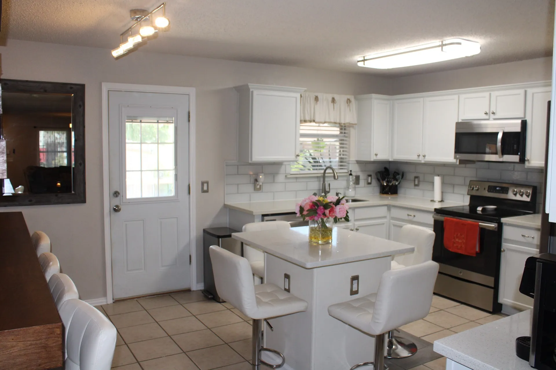Kitchen featuring white cabinetry, subway tile backsplash, stainless steel appliances, and a central island with countertop seating