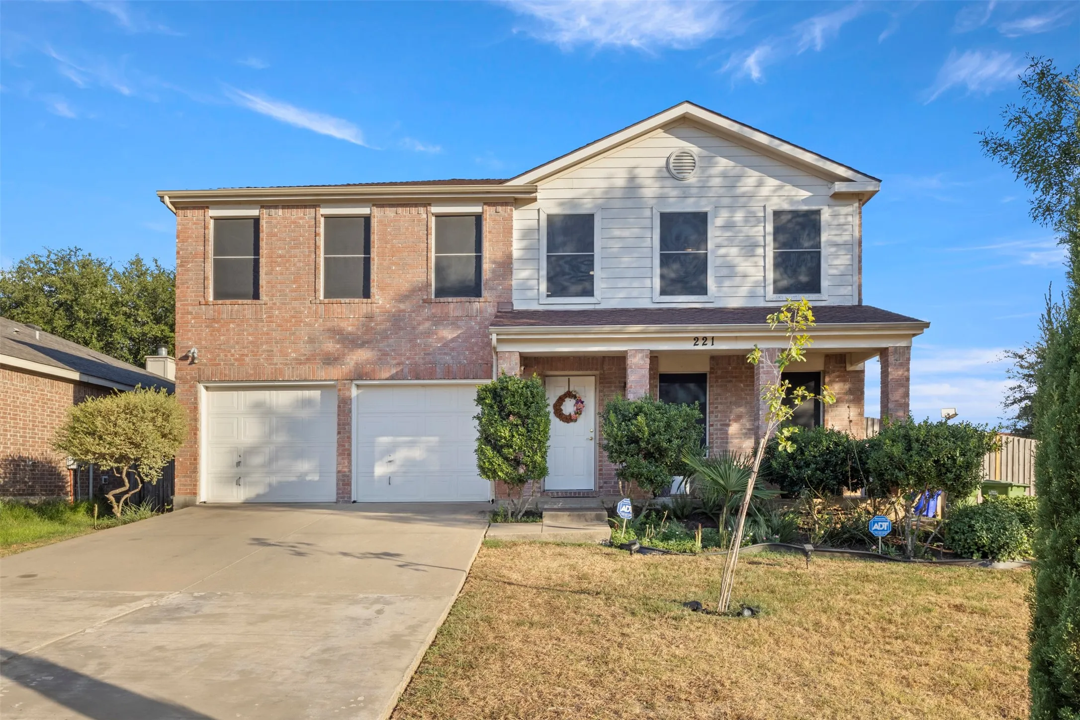 Brick exterior with white siding accents, covered front porch, and a two-car garage