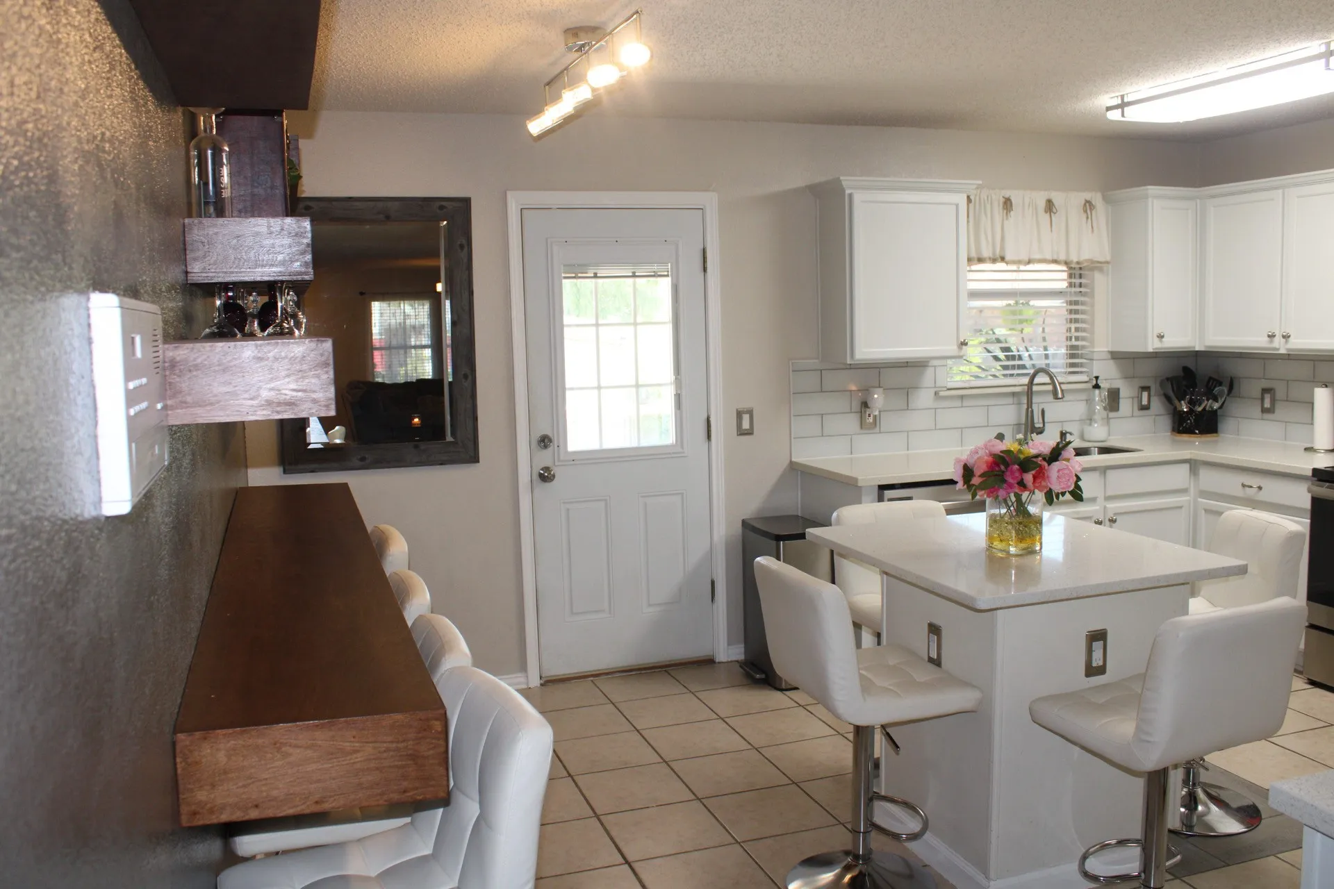 White cabinetry with modern hardware, subway tile backsplash, and light-toned countertops