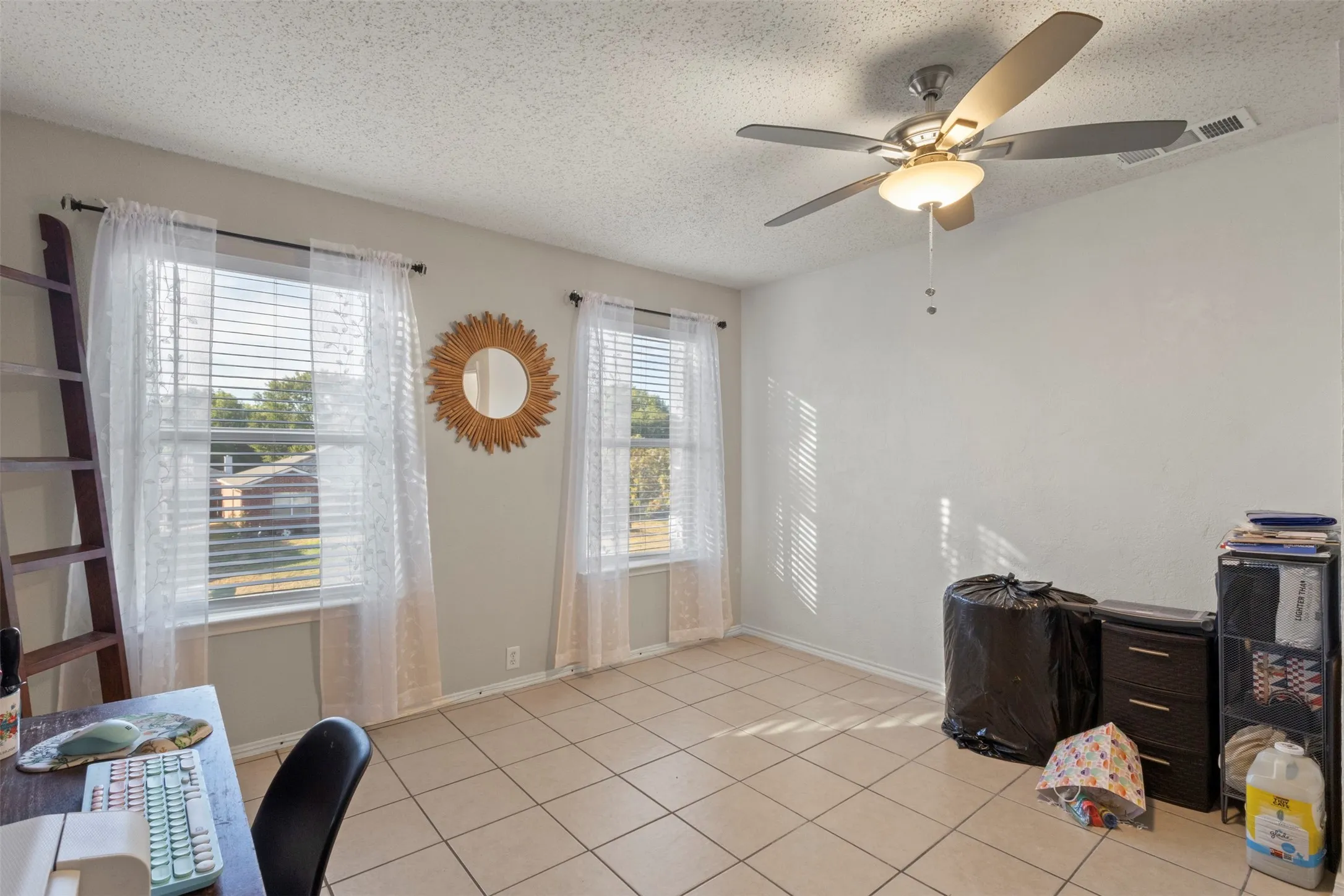Tile flooring, two windows, ceiling fan with integrated lighting, and neutral wall tones