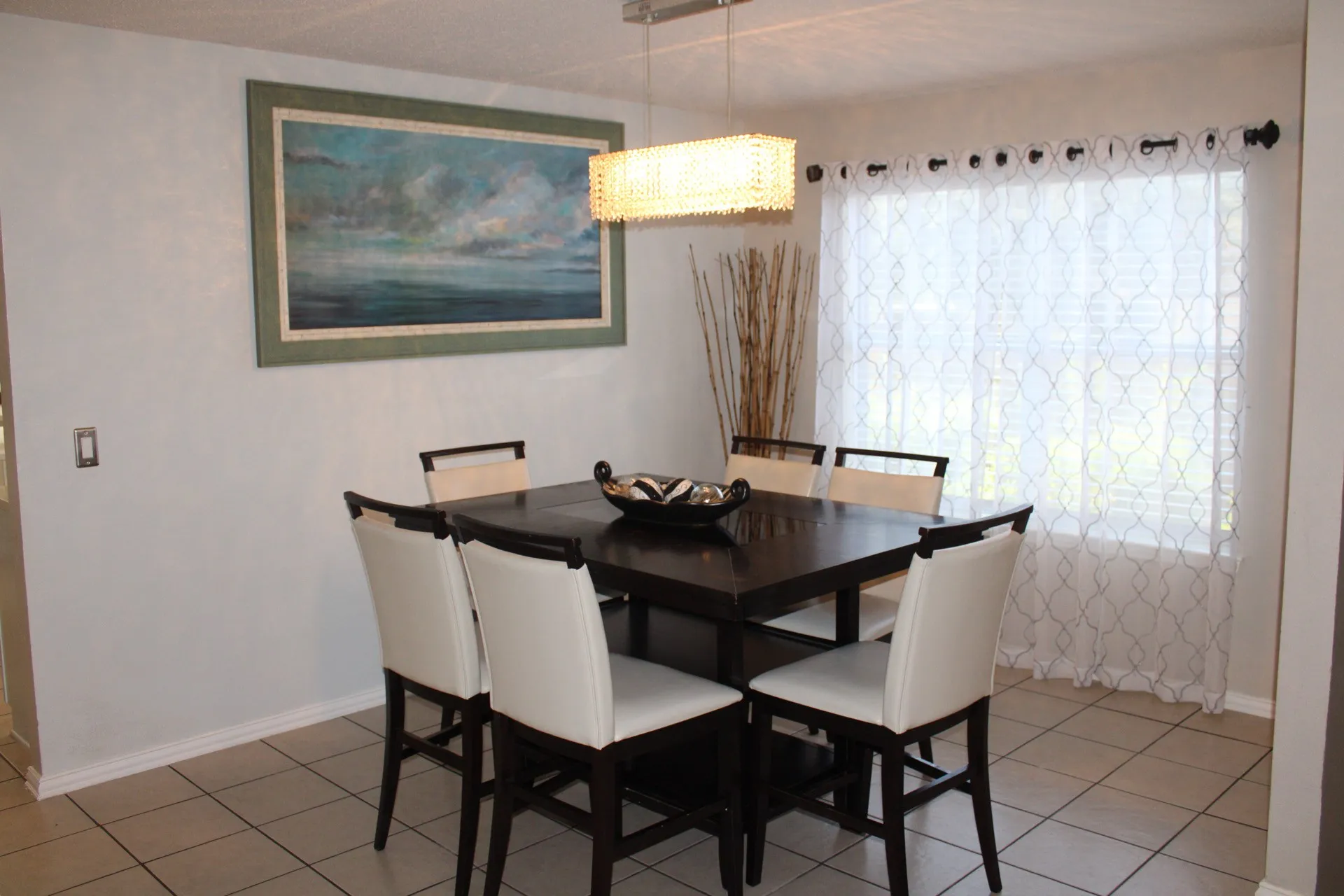 Ceramic tile flooring, textured wall finish, and a rectangular window with sheer coverings