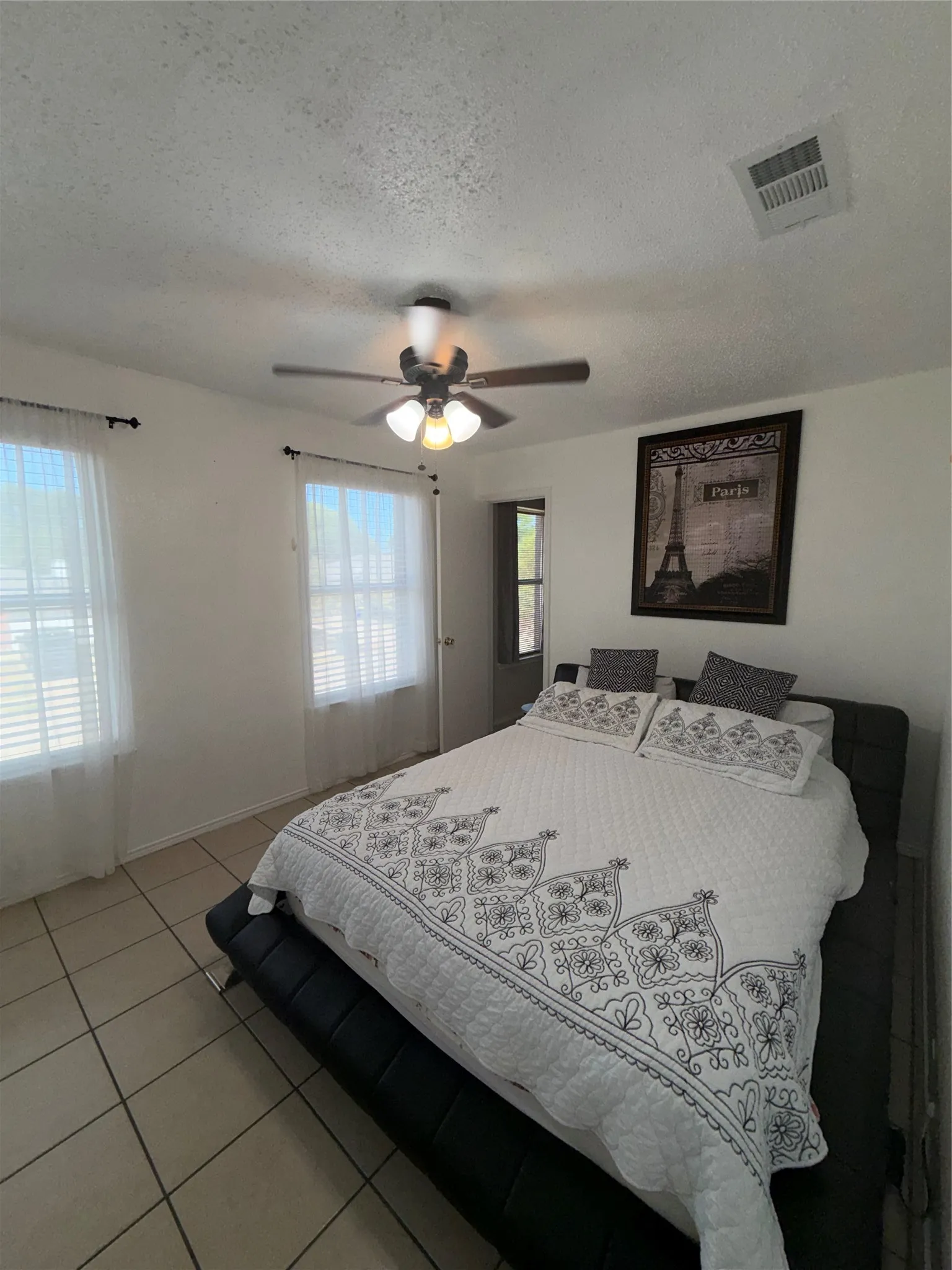 Tile flooring, ceiling fan with integrated lighting, multiple windows, white walls, and a white ceiling
