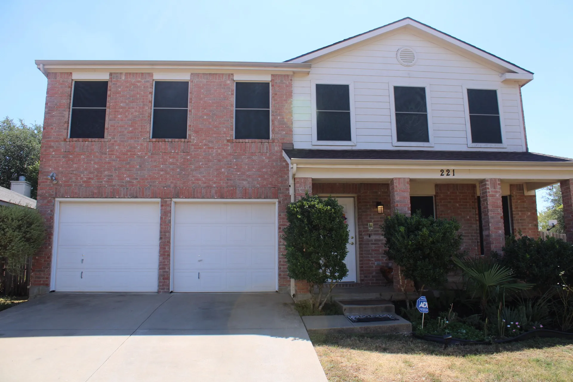 Brick and siding exterior with a covered front porch, two-car garage, and concrete driveway