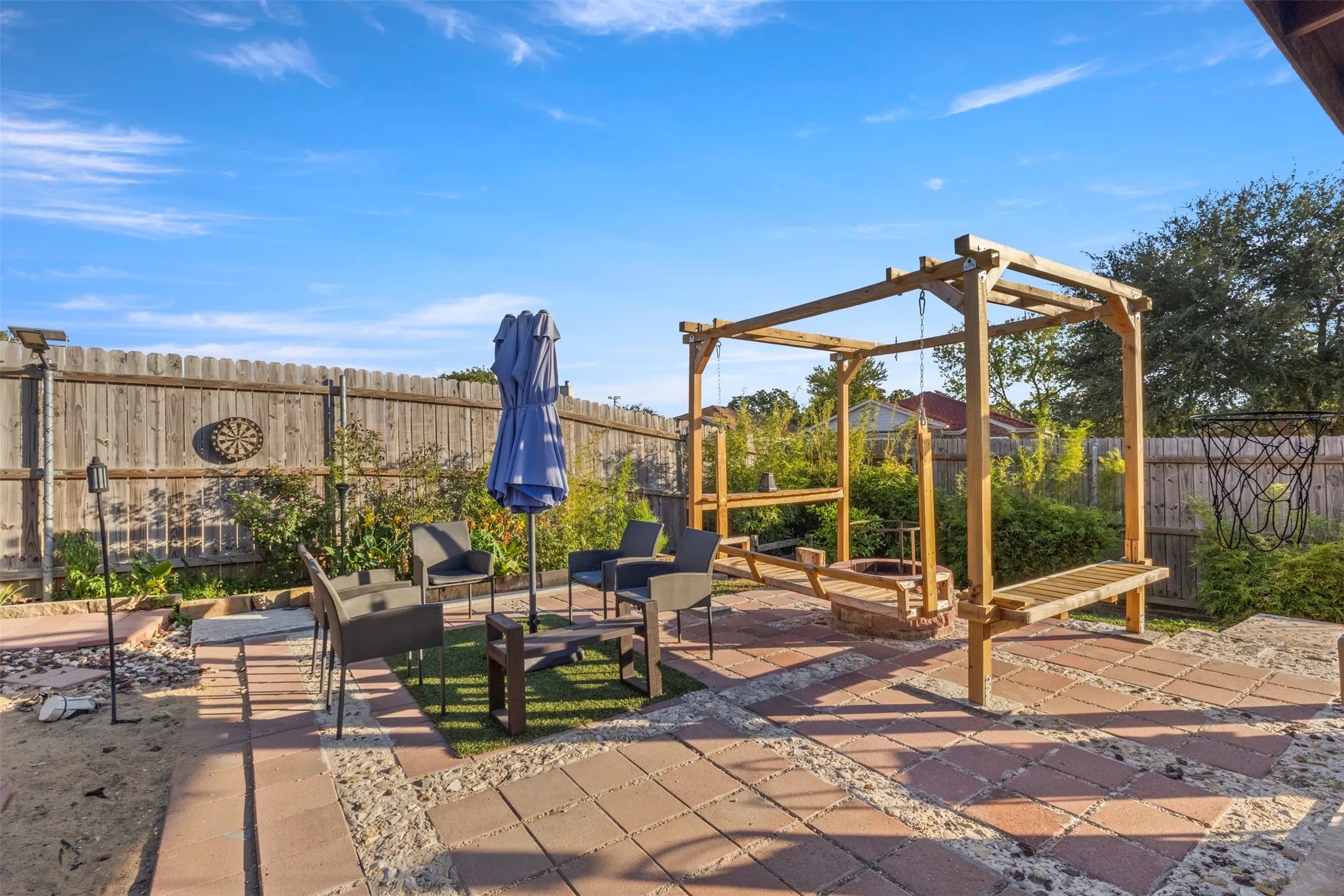 Hardscaping patio with paver and stone accents, wood privacy fencing, and a built-in pergola structure