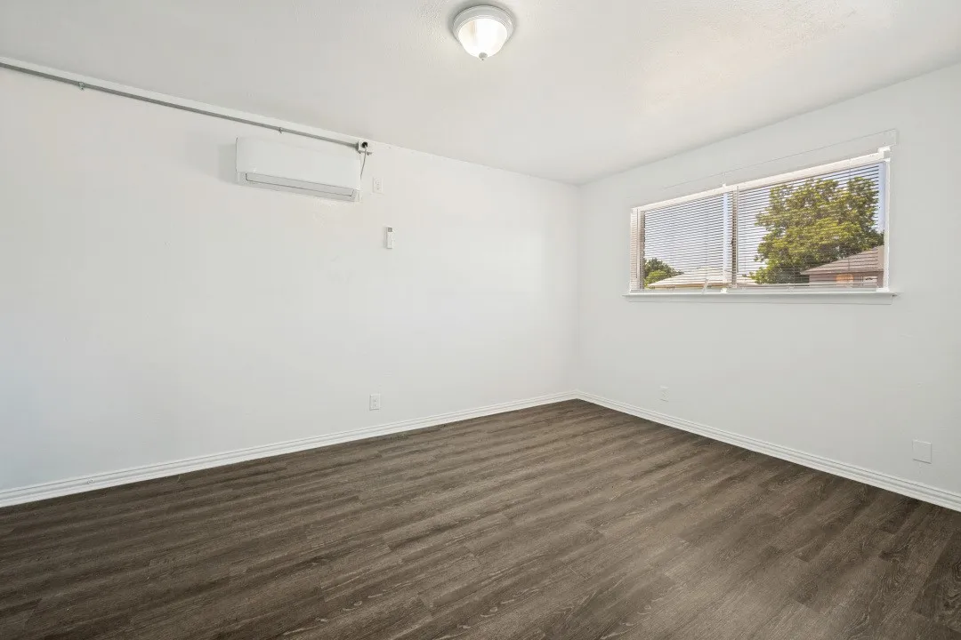 Wood-finish flooring, white walls, flush mount ceiling light, and a horizontal window with blinds
