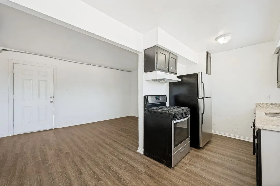 Wood-finish flooring throughout, kitchen with dark cabinetry, stainless steel refrigerator, and a gas range