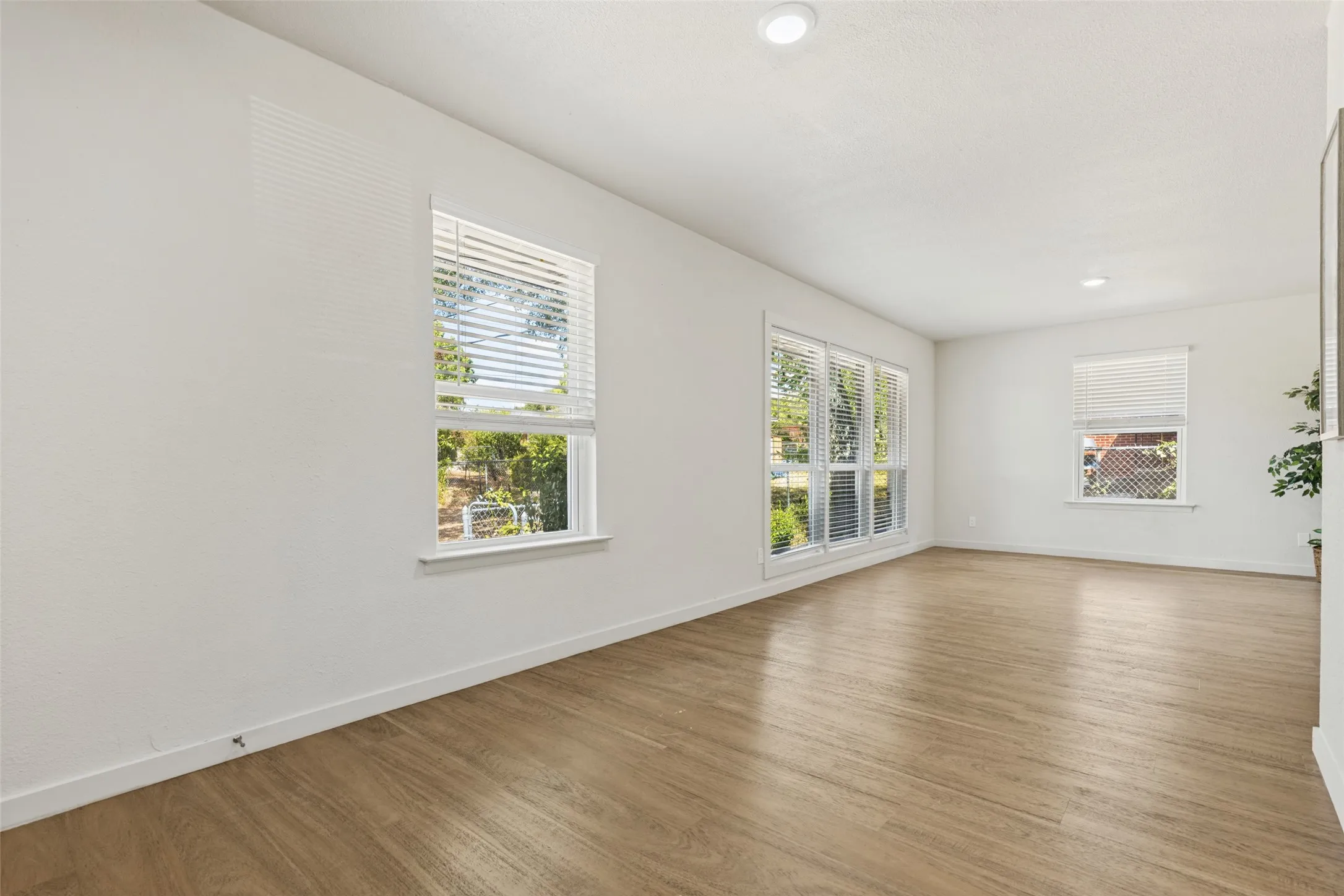 Wood-finish flooring, multiple windows with blinds, recessed lighting, and white​​‌​​​​‌​​‌‌​‌‌​​​‌‌​‌​‌​‌​​​‌​​ walls