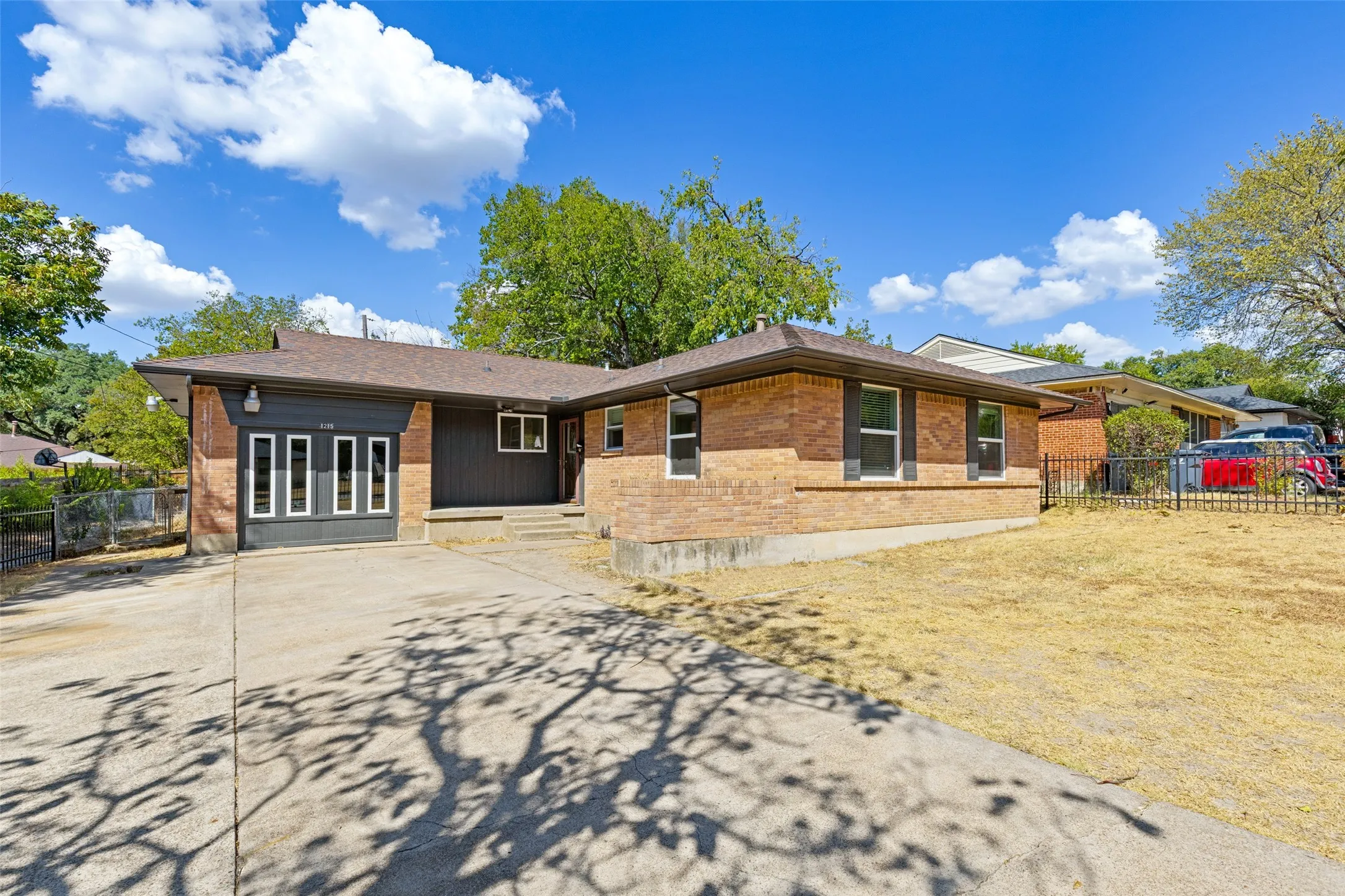 Brick exterior featuring dark window shutters, an attached garage with window panels, and a concrete driveway