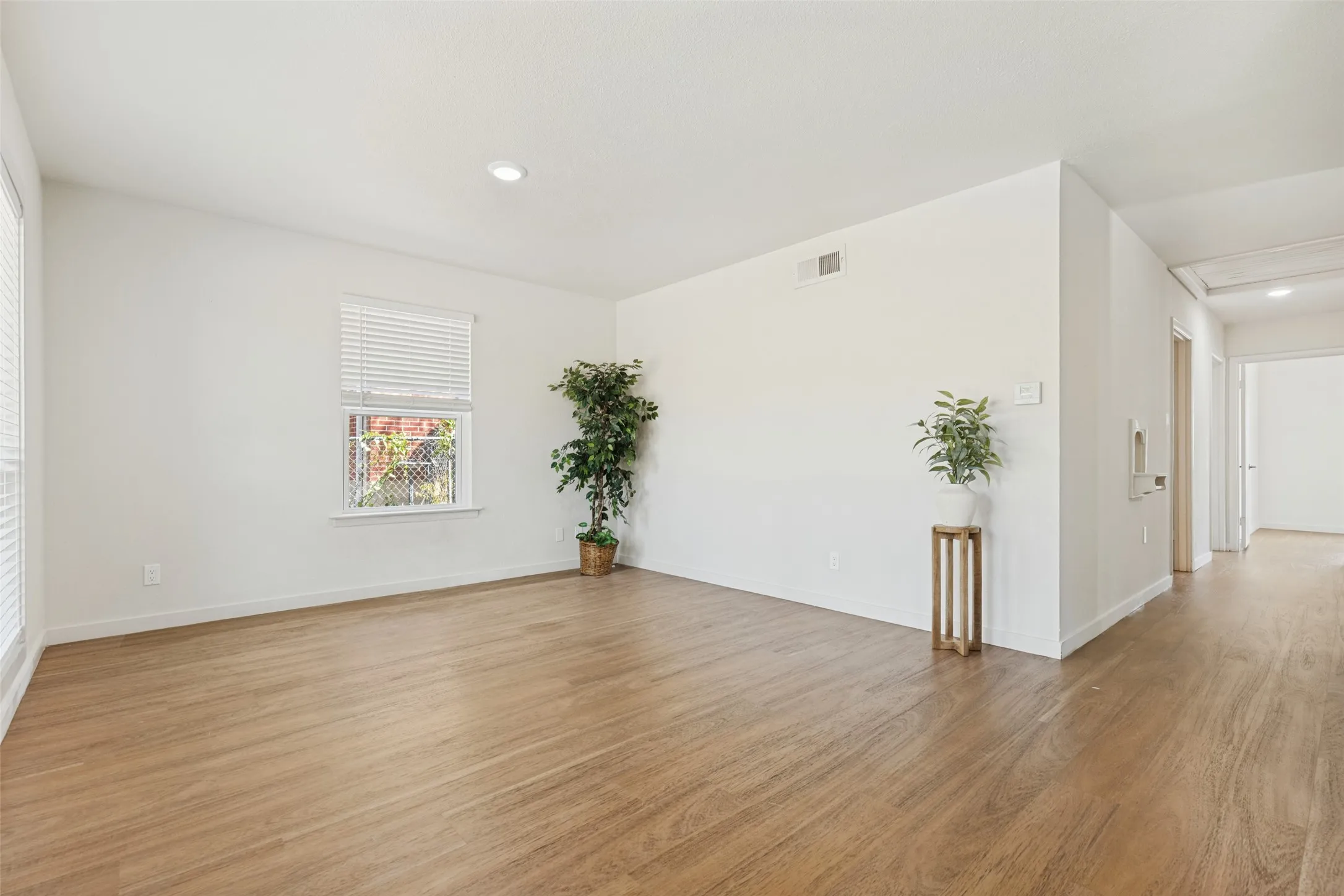 Wood-finish flooring throughout, white walls, recessed lighting, and multiple windows with blinds