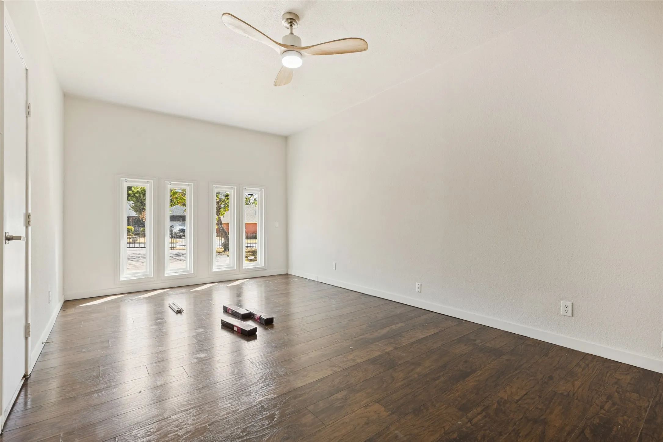 Vaulted ceiling with a ceiling fan, wood-finish flooring, and multiple vertical windows