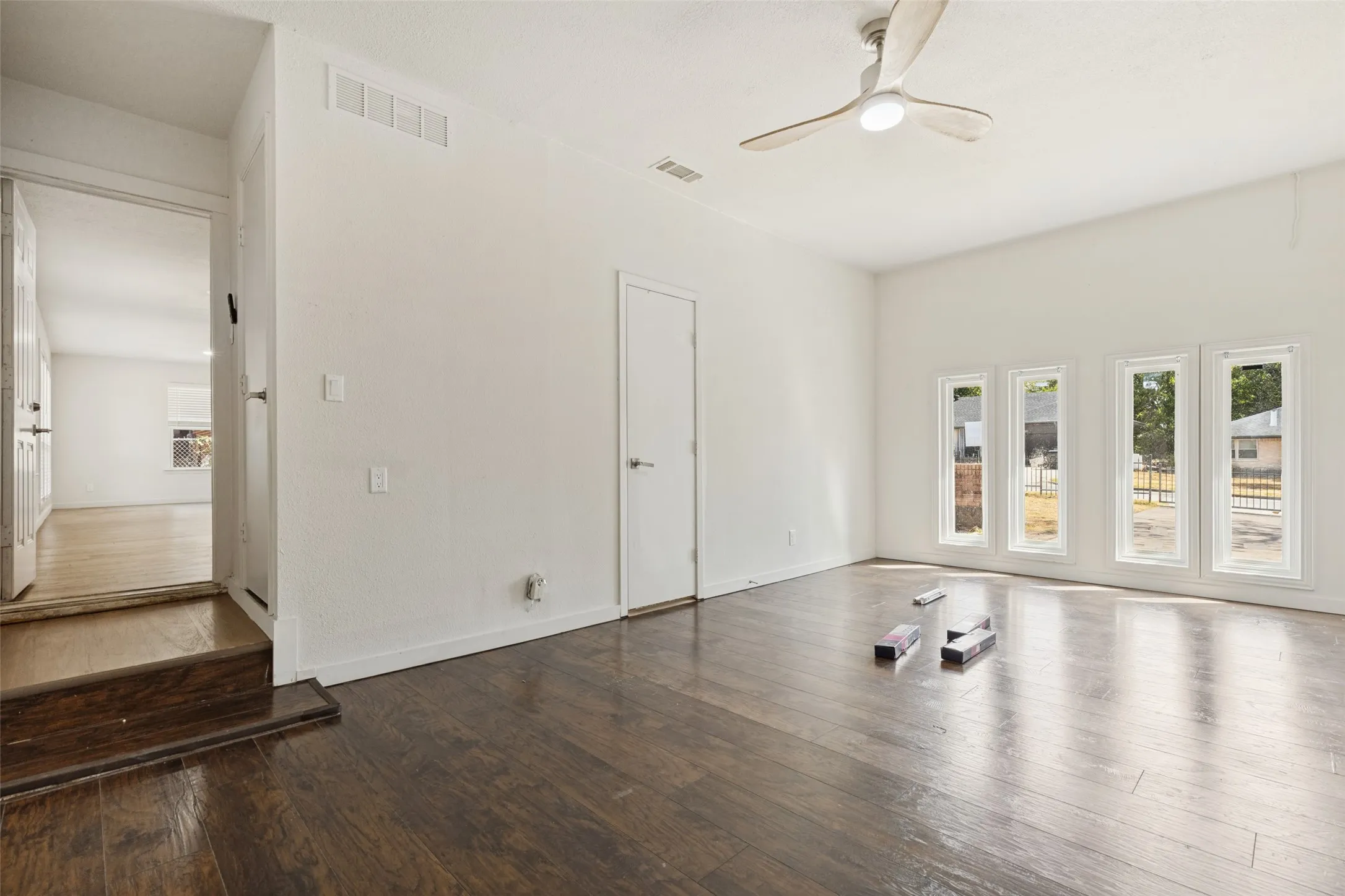 Dark wood-finish flooring, vaulted ceiling, contemporary ceiling fan, and a wall of four tall windows