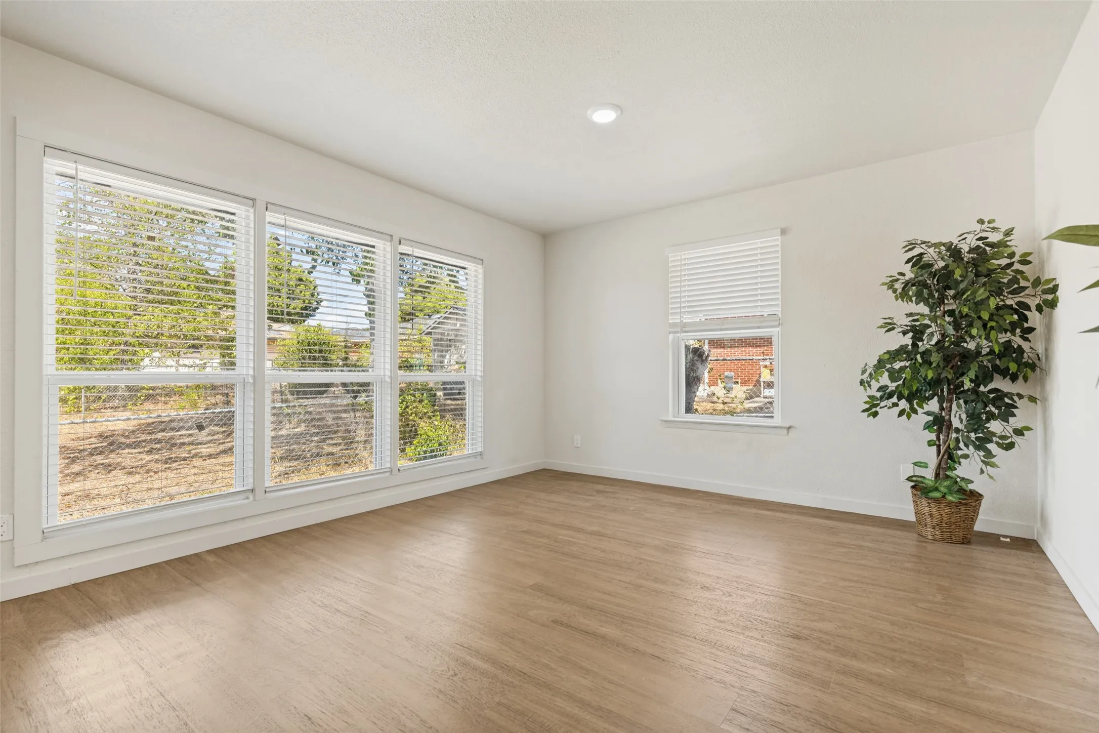 Expansive windows, light wood-finish flooring, recessed lighting, and crisp white walls