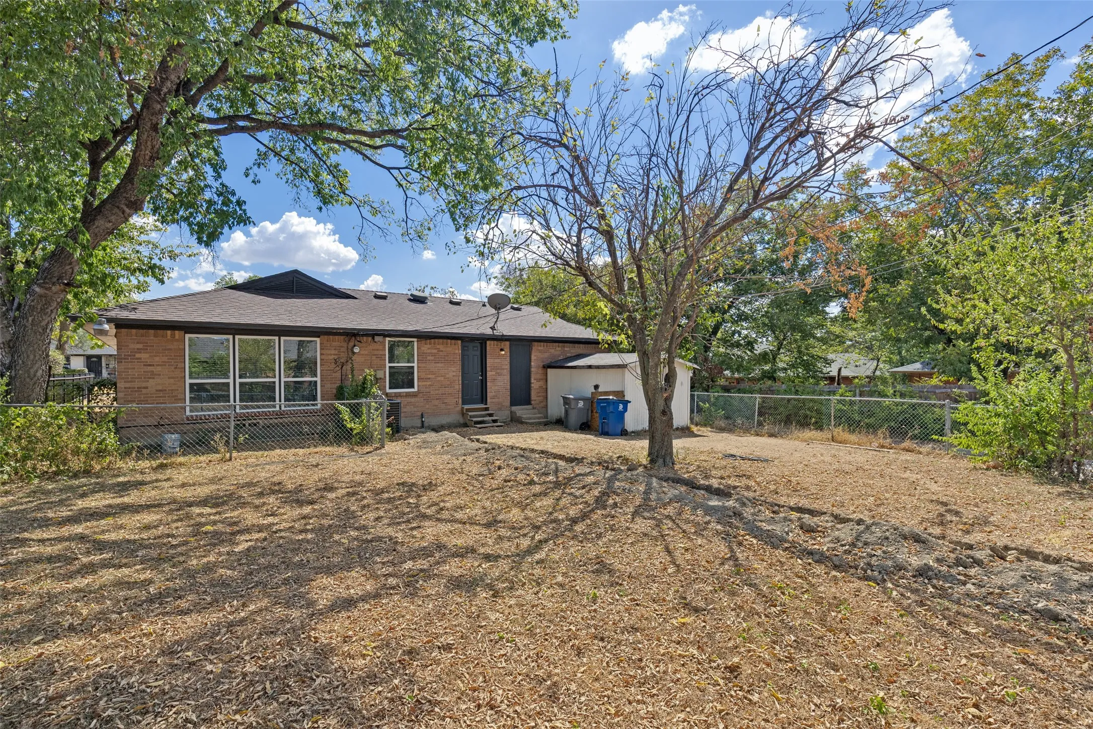 Brick exterior with multiple windows and a dark shingle roof