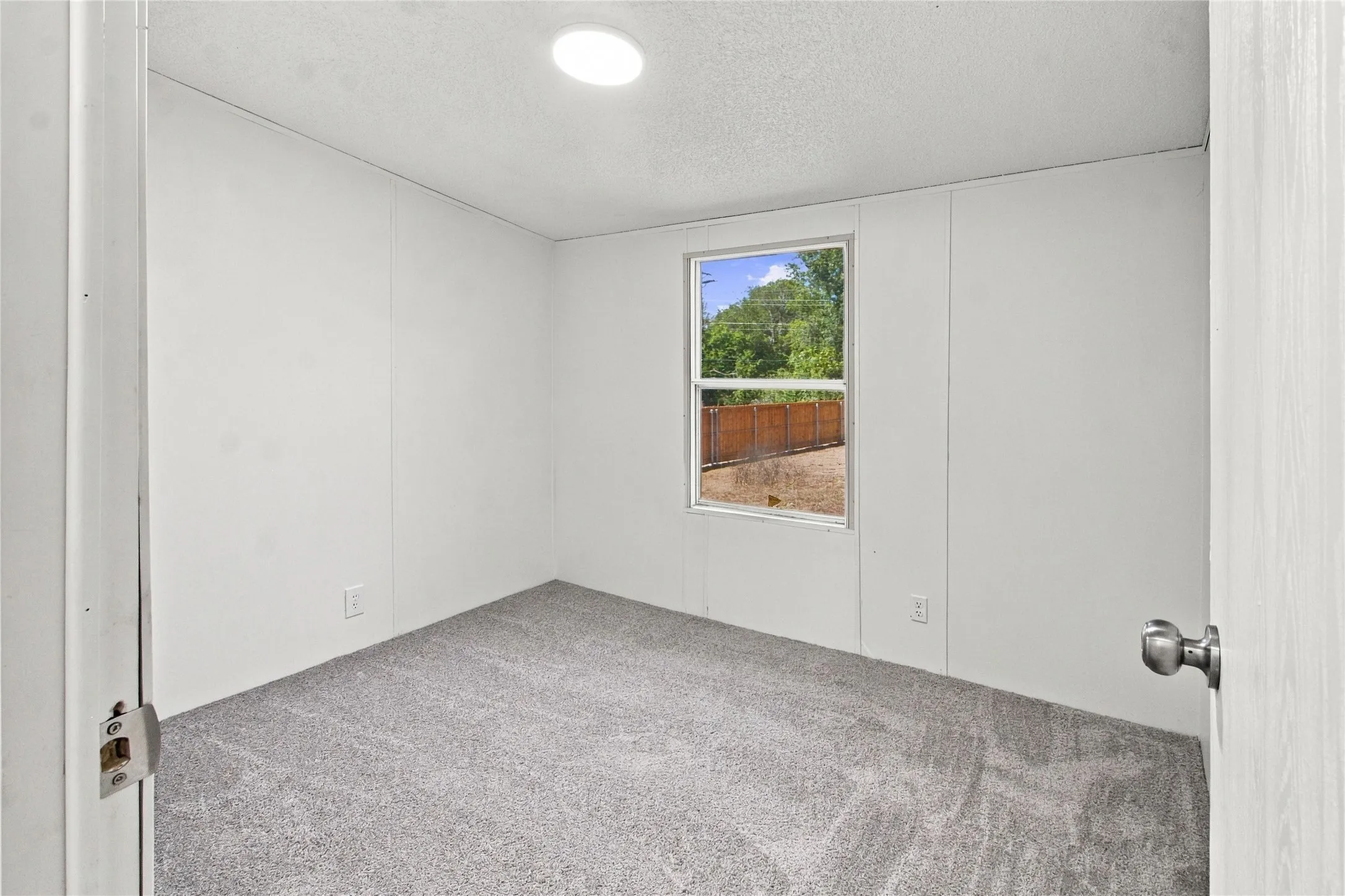 Recessed ceiling light, paneled walls, gray carpet flooring, and a single window