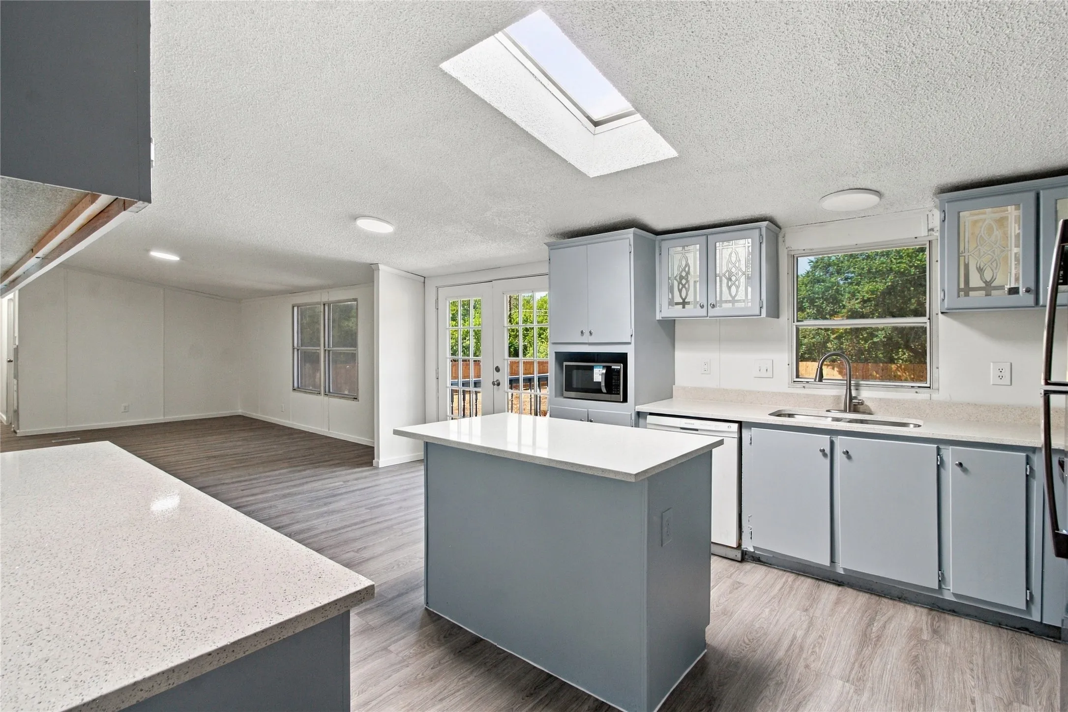 Kitchen featuring a skylight, white countertops, built-in microwave, and wood-finish flooring