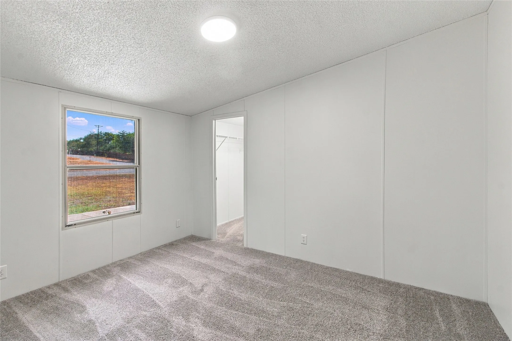 Gray textured carpeting, white paneled walls, and a recessed ceiling light fixture