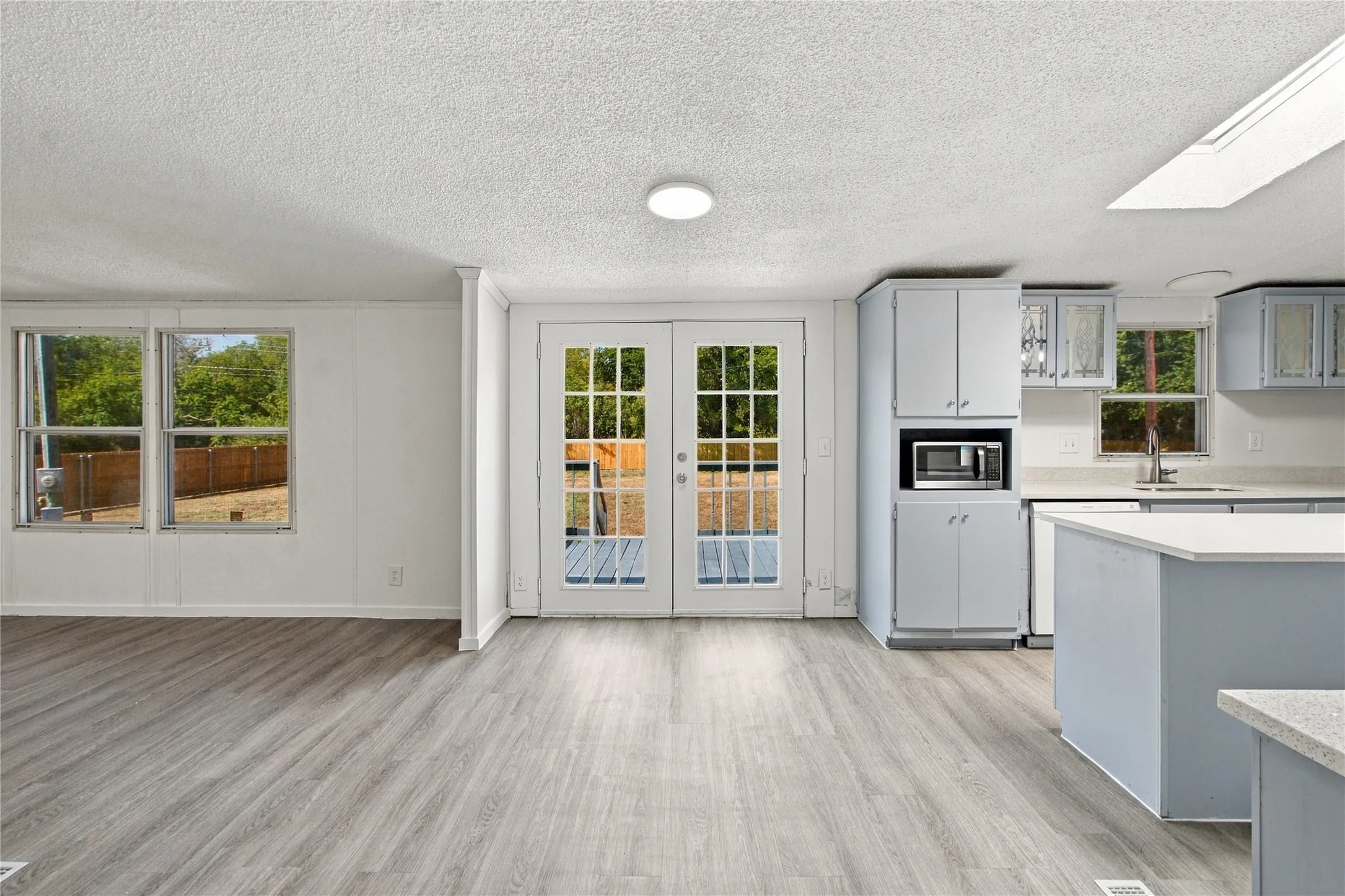 Wood-finish flooring throughout, light-toned cabinetry, light countertops, and a skylight
