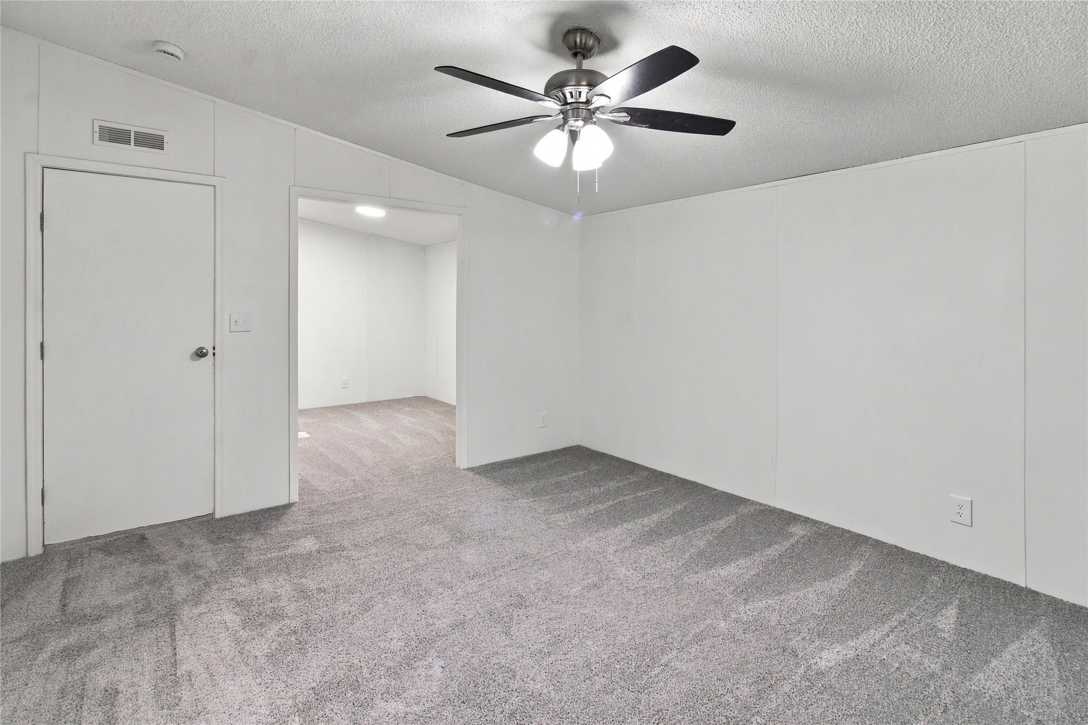 Neutral tone wall panels, gray carpet flooring, ceiling fan, and recessed lighting