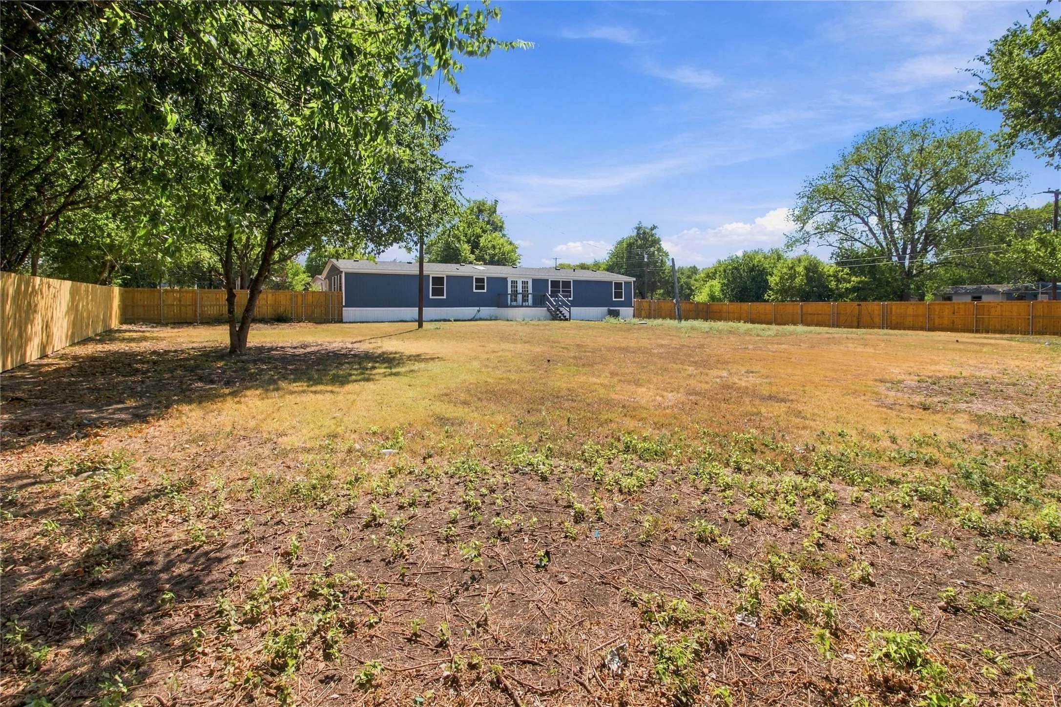 Expansive yard featuring mature trees and a wood privacy fence