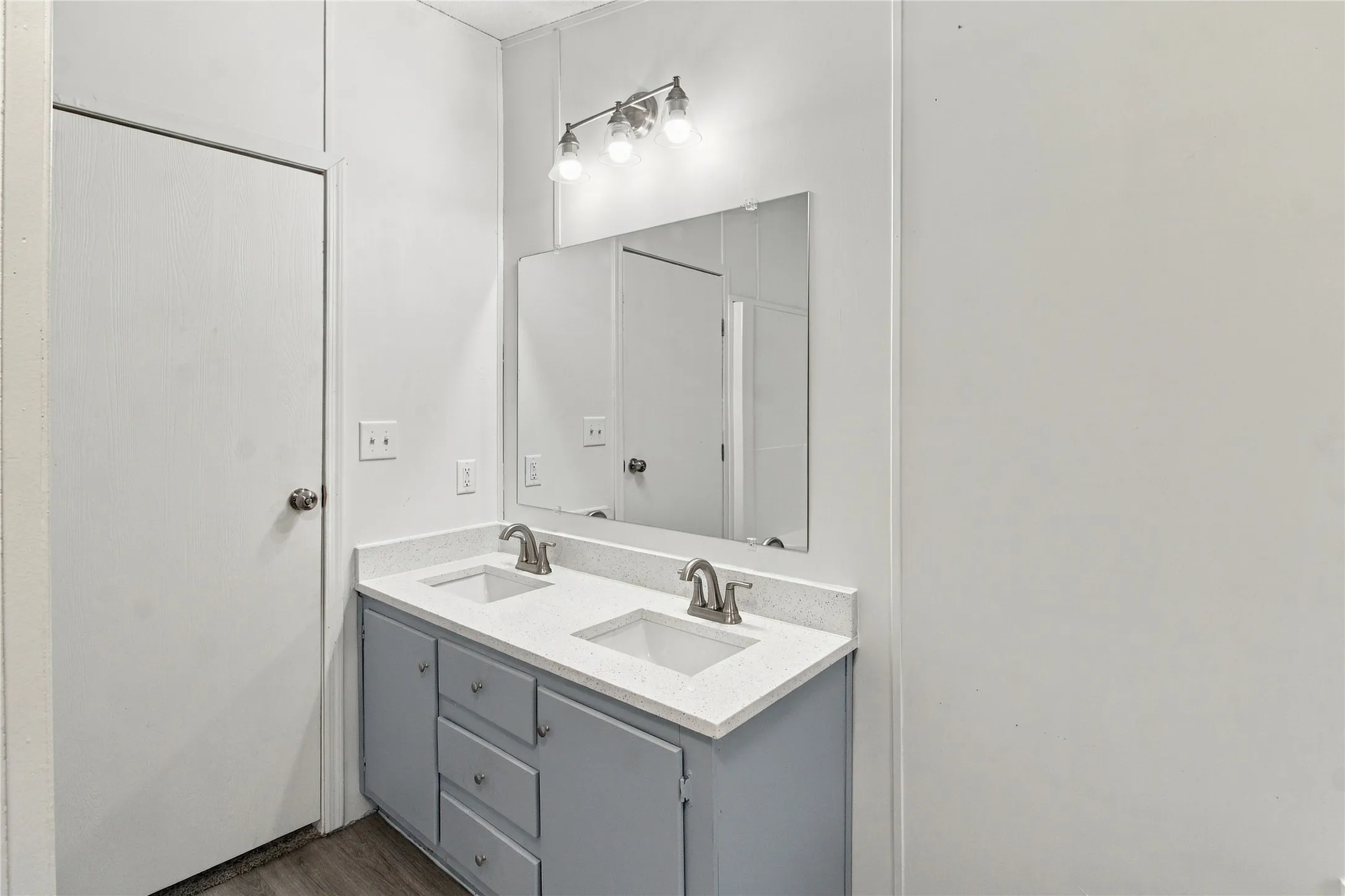 Double vanity with integrated sinks, light gray cabinetry, and brushed nickel fixtures
