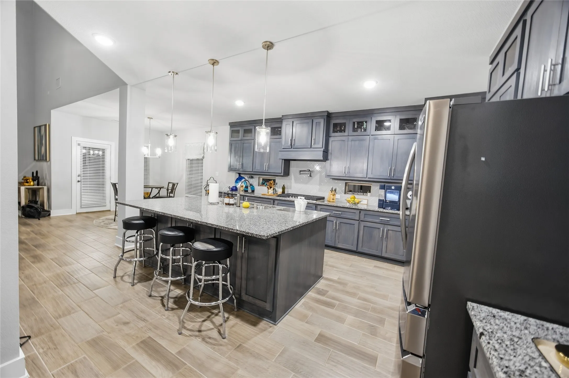 Kitchen featuring wood-finish flooring, an island with stone countertop, pendant lighting, and grey cabinetry