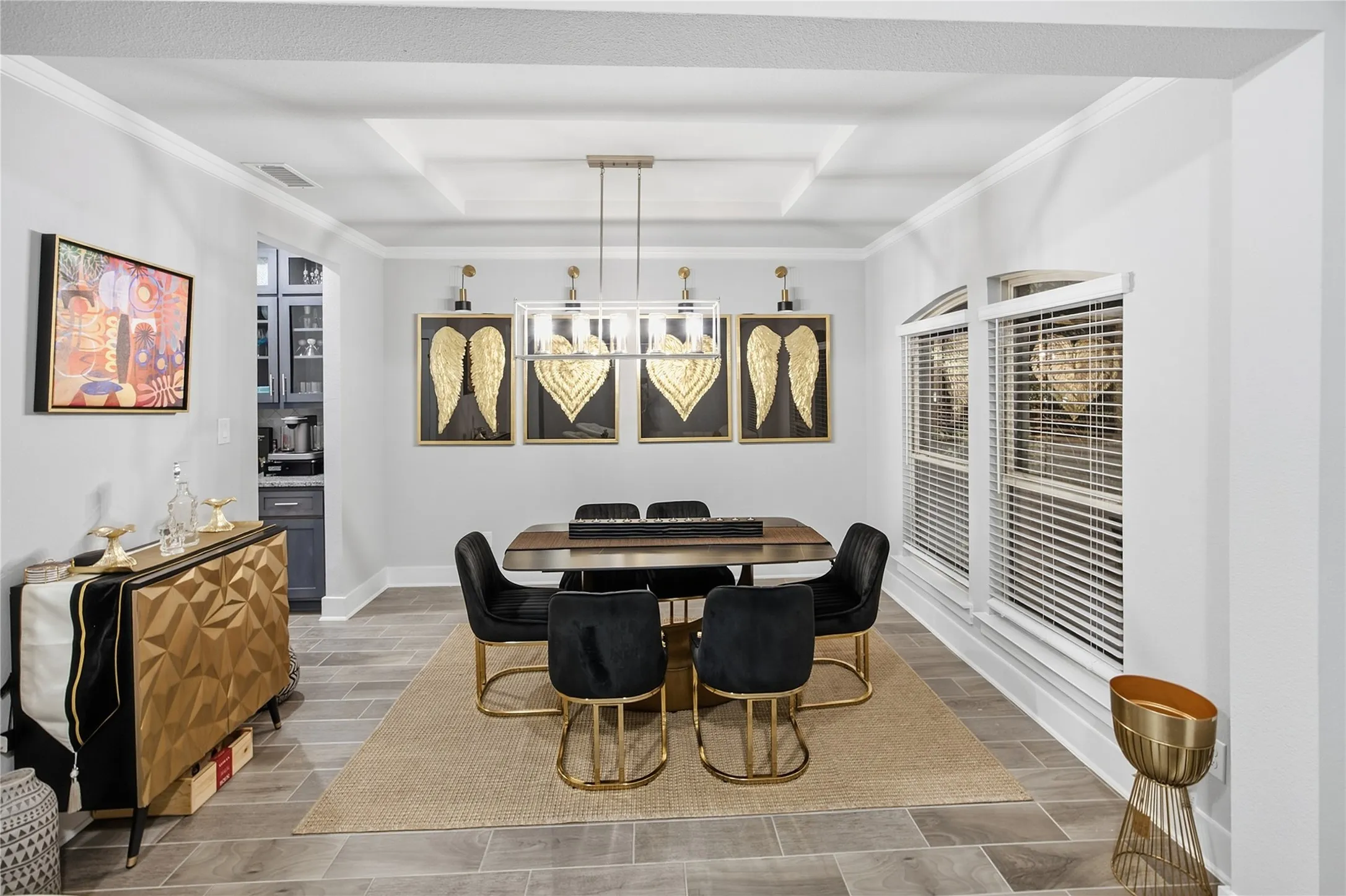 Crown molding, recessed ceiling detail, wood-finish flooring, two arched windows with blinds, and built-in cabinetry in the background