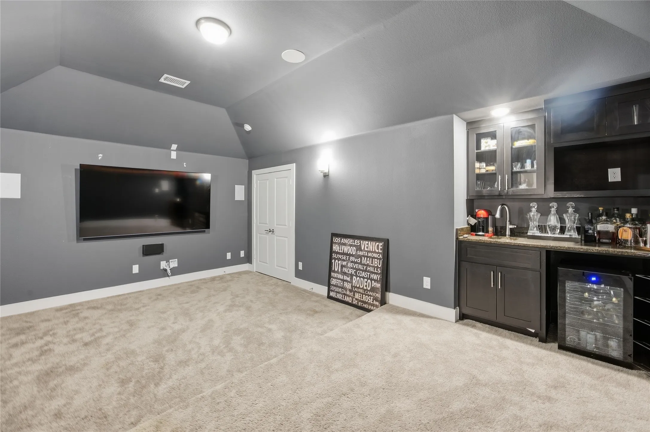 Built-in wet bar with dark cabinetry, integrated sink, and stone-look countertop