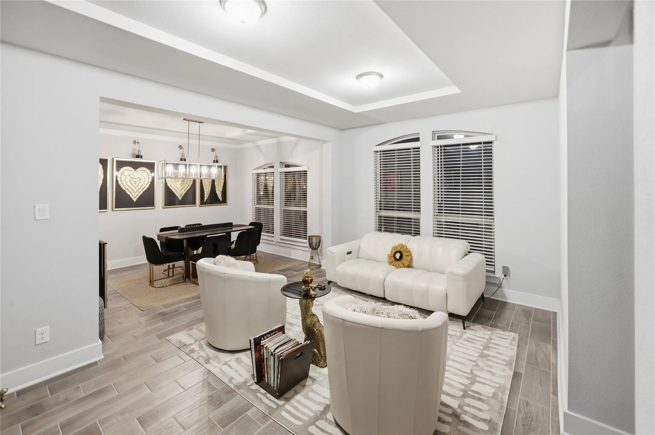Recessed lighting, tray ceiling, arched window, wood-finish flooring, and a contemporary chandelier