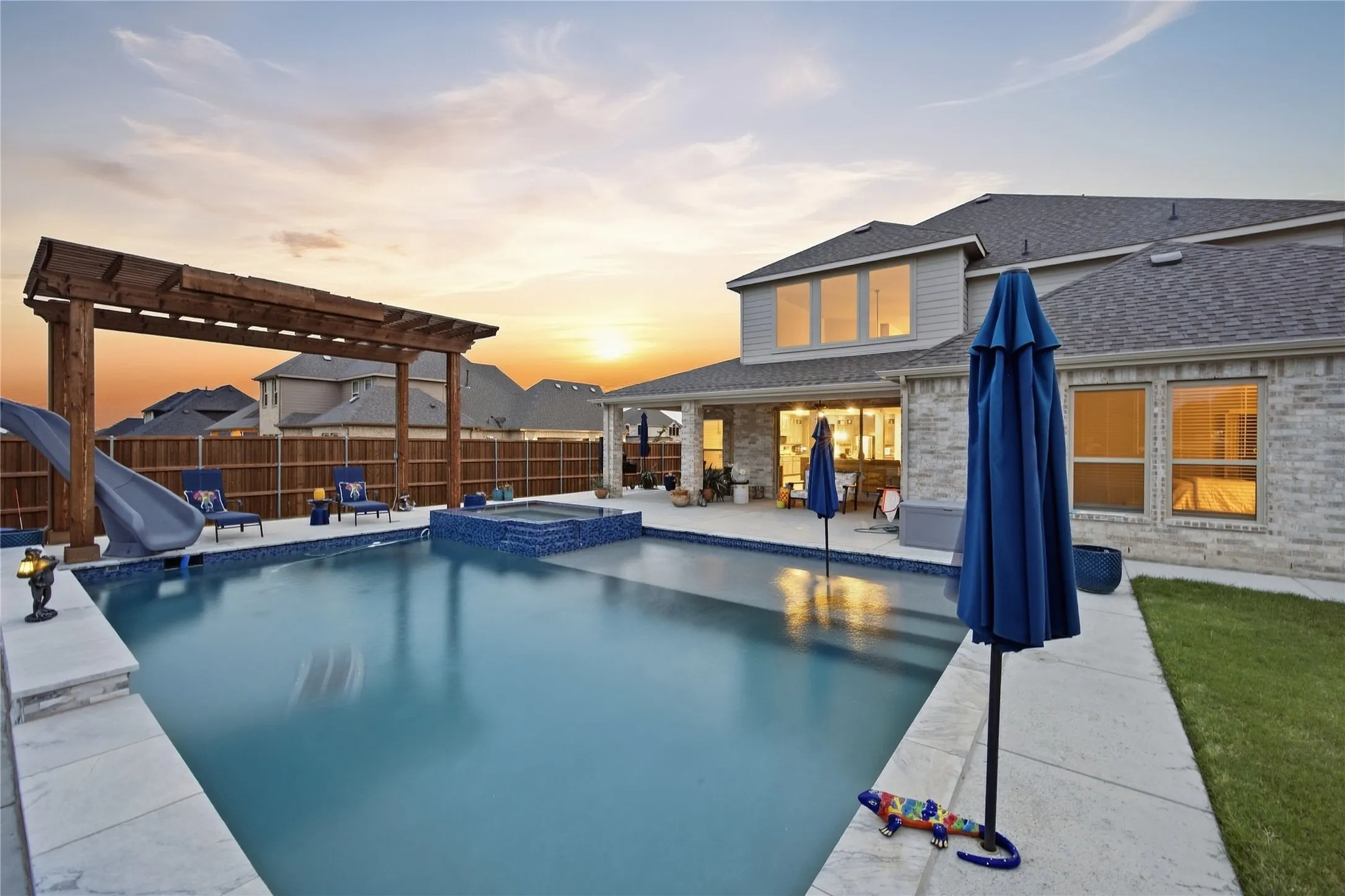 Expansive backyard featuring a built-in swimming pool, integrated spa, and a wood pergola