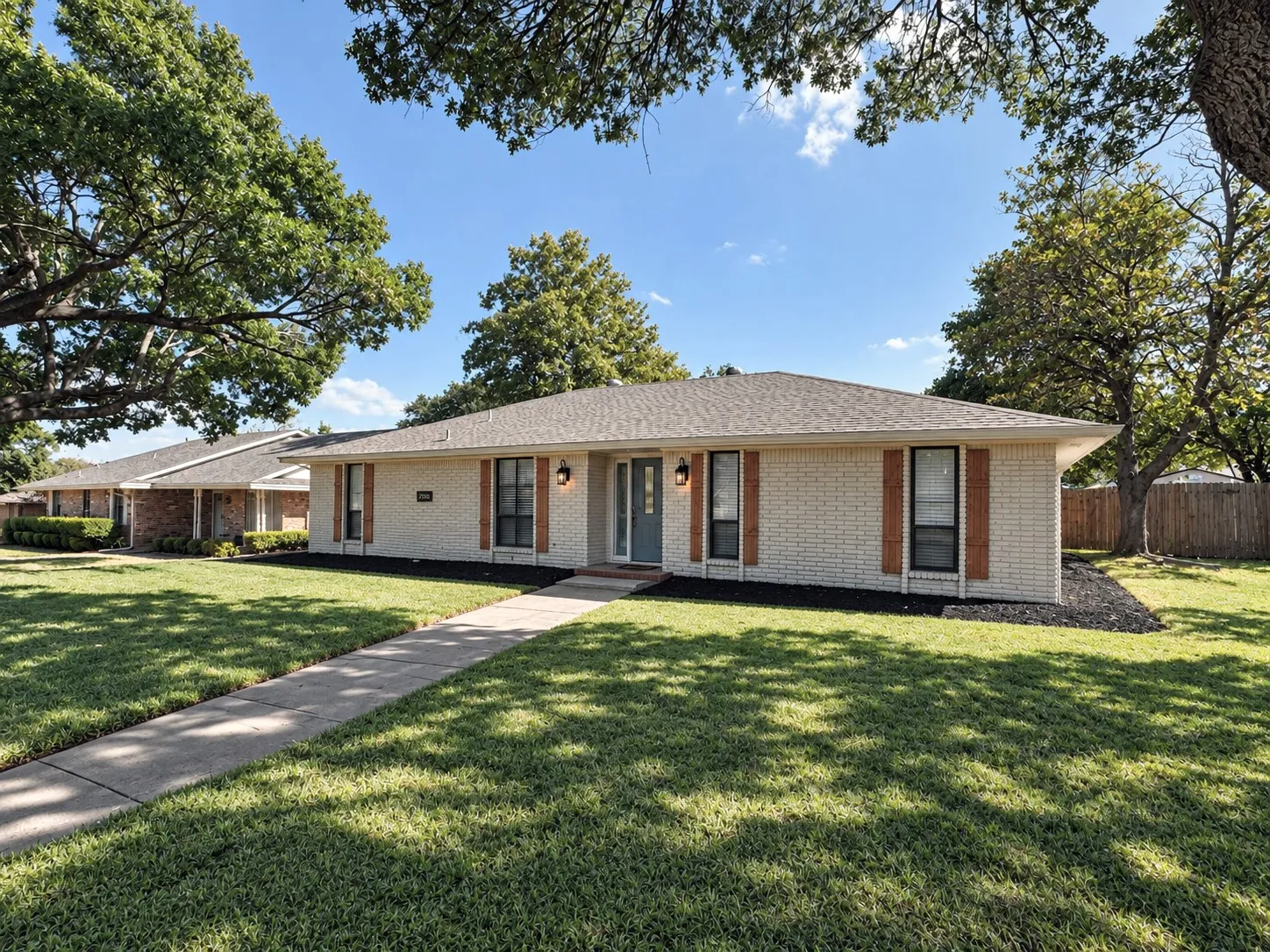 Light brick exterior with wood shutters, a covered entry, and a concrete walkway