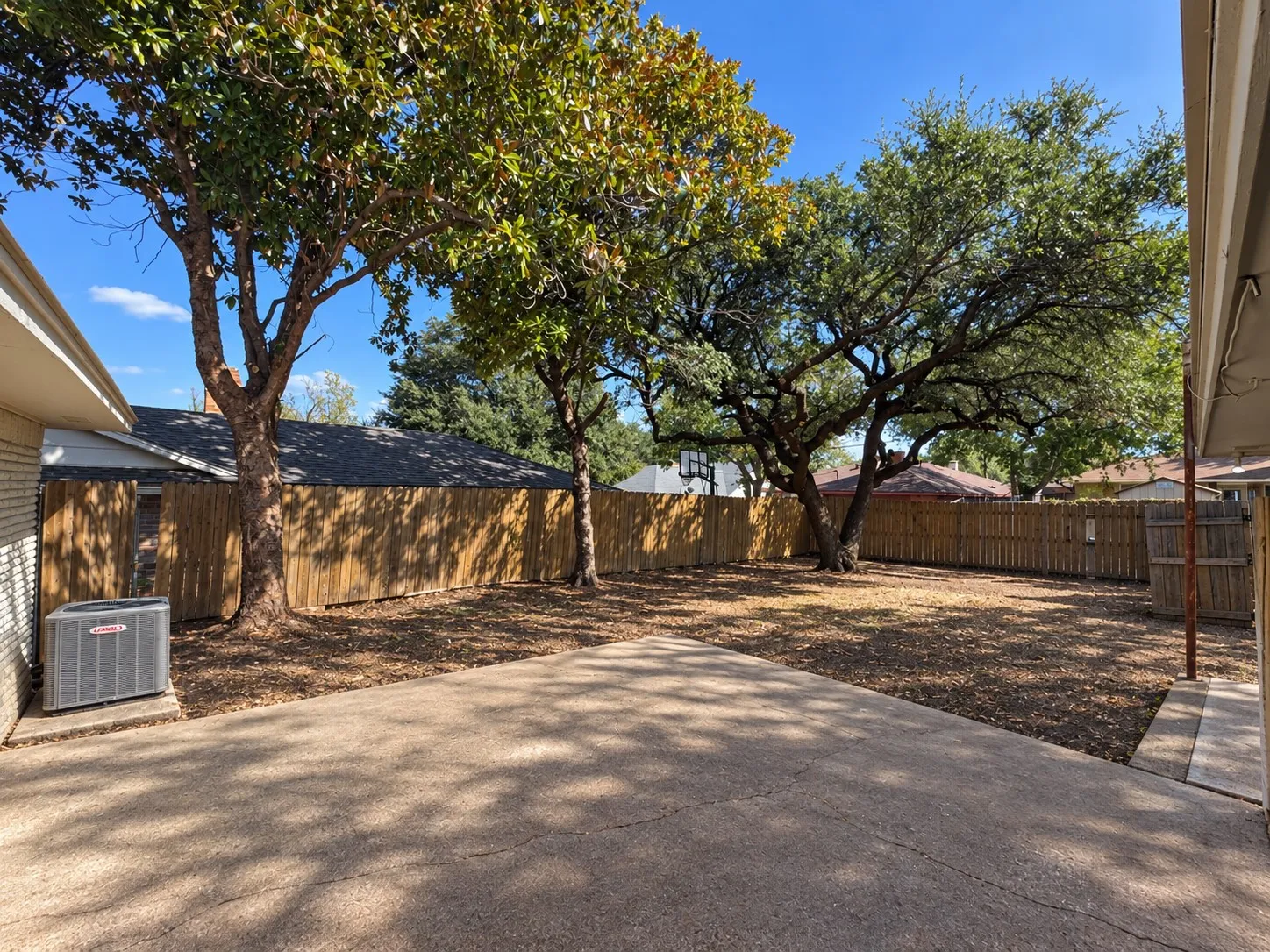 Concrete patio with mature trees and wood fencing