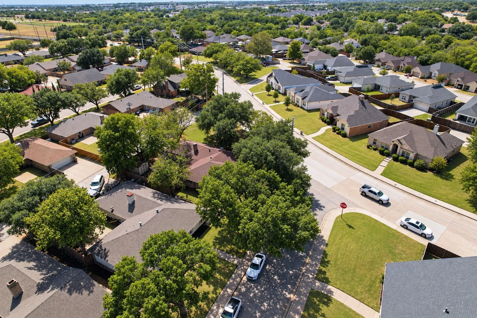 Residential neighborhood with mature trees, paved streets, and sidewalks