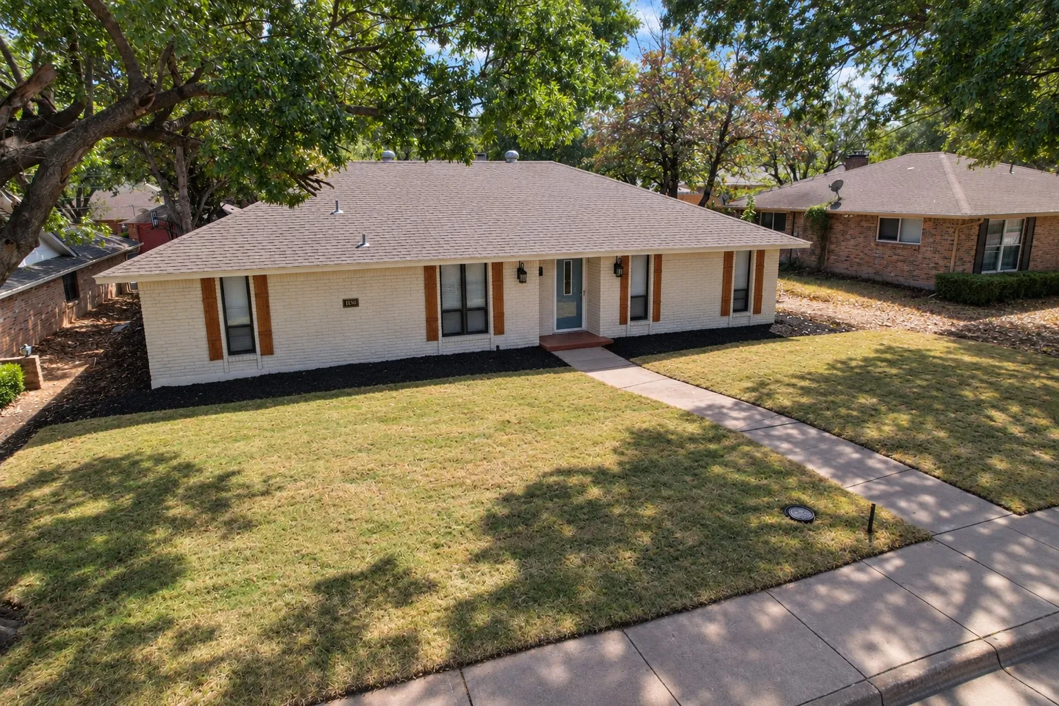 Ranch-style exterior with wood shutters, a covered entry, and a concrete walkway