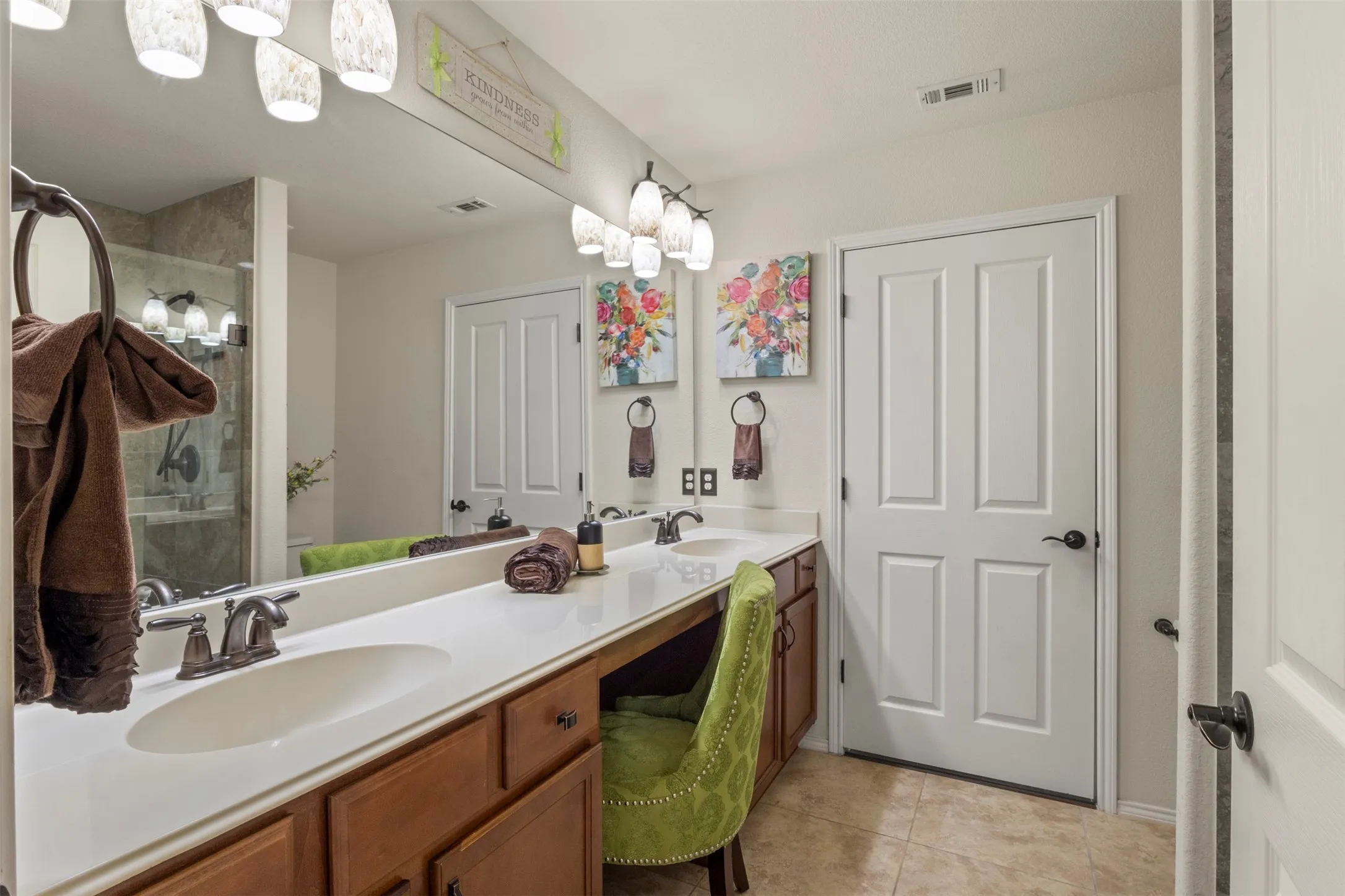 Dual vanity with integrated sinks, expansive counter space, wood-finish cabinetry, and tiled flooring