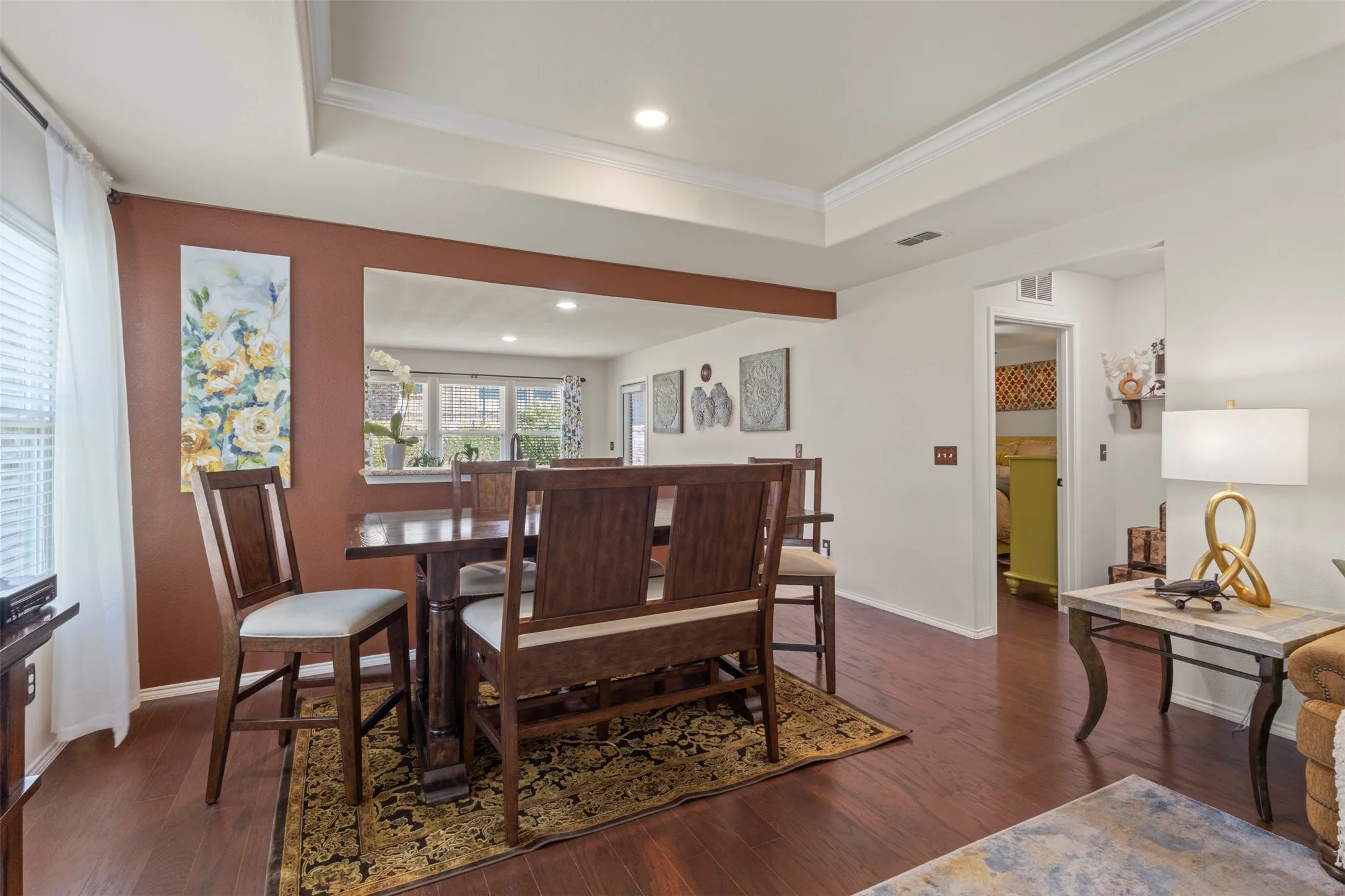 Wood-finish flooring throughout, tray ceiling with recessed lighting, and a wide cased opening