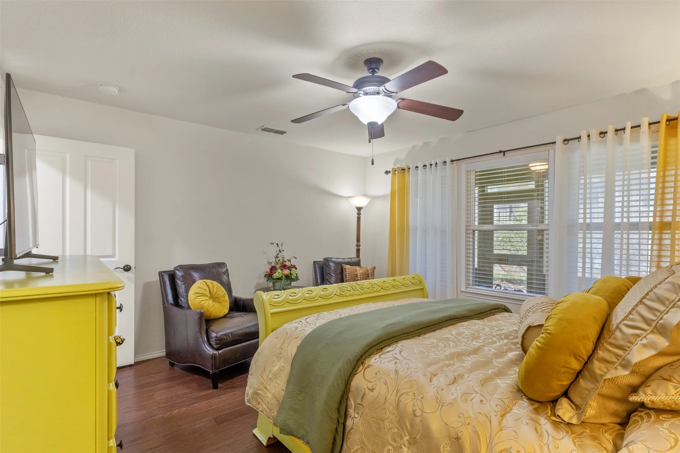 Hardwood-finish flooring, ceiling fan with integrated lighting, window with blinds, and white interior door