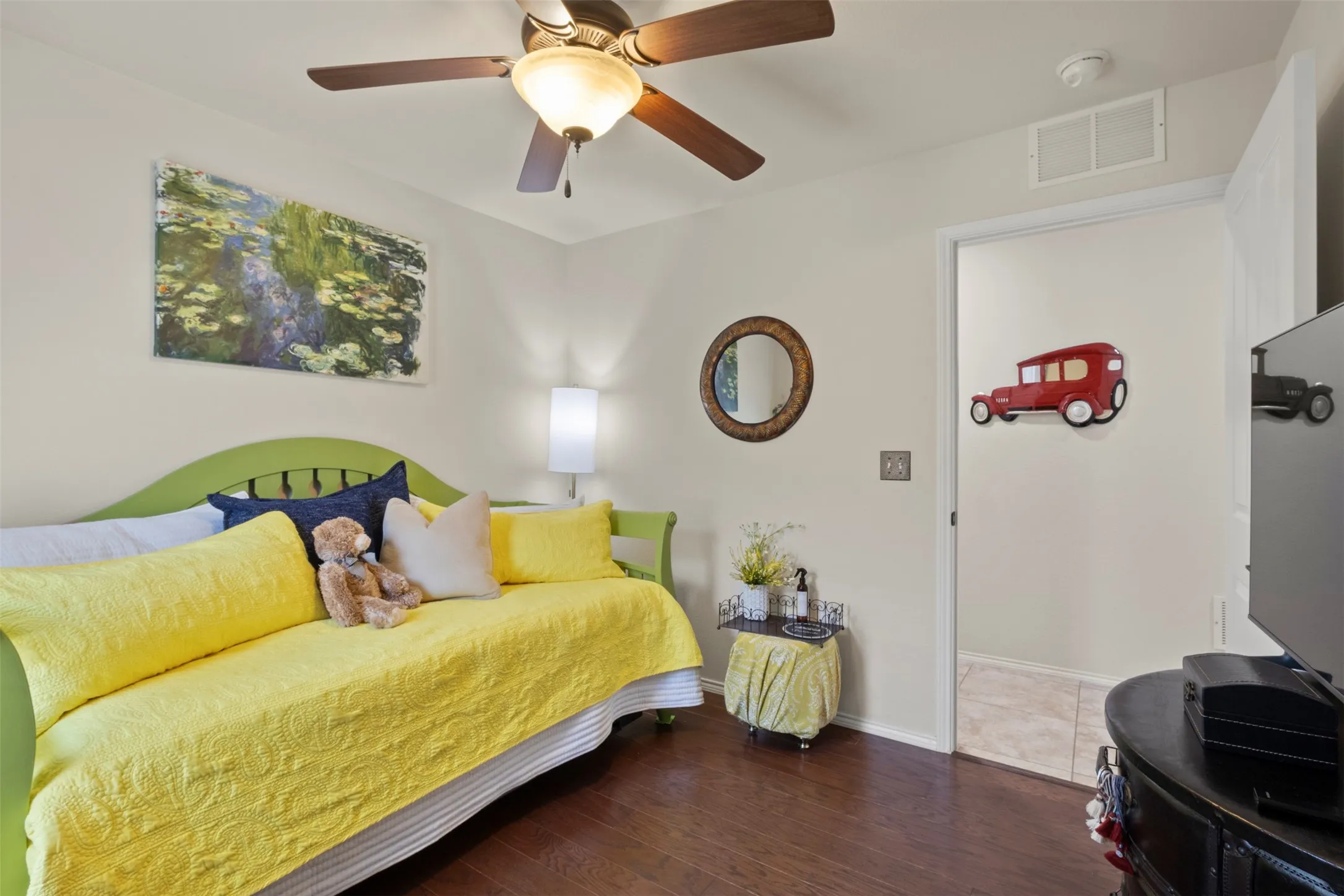 Wood-finish flooring, ceiling fan with integrated lighting, and a wall-mounted light fixture